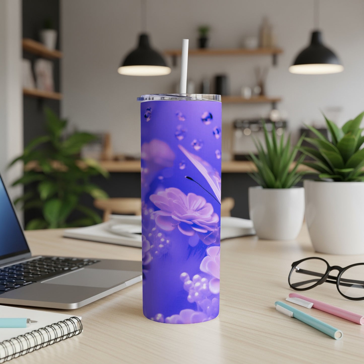 Purple tumbler with floral and butterfly design, on a desk.