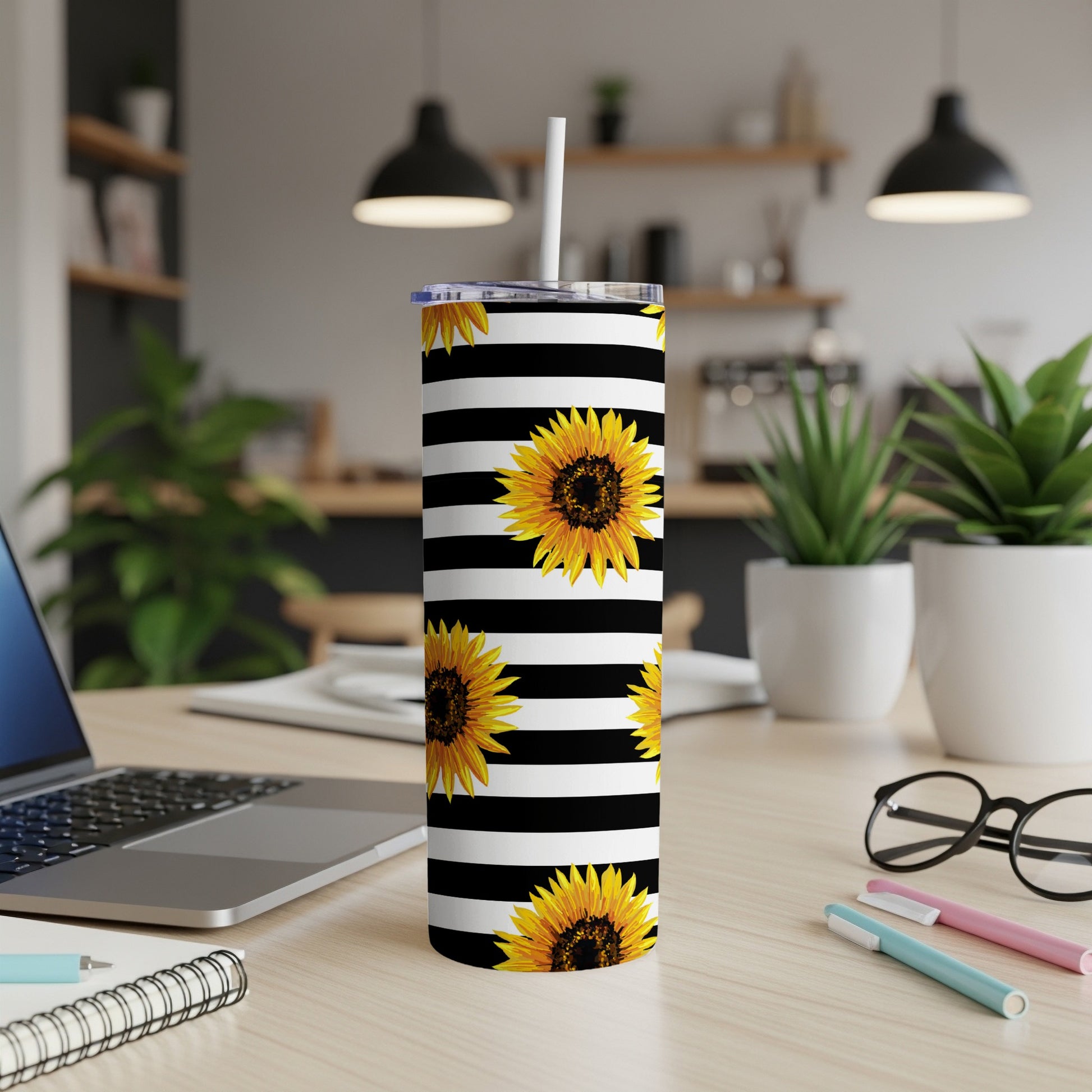 Tumbler with black and white stripes and sunflowers, with a straw and lid.