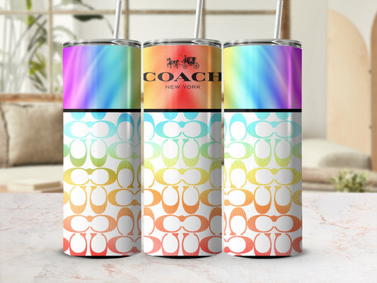 Three Coach tumblers with rainbow tie-dye, logo pattern, and straw.