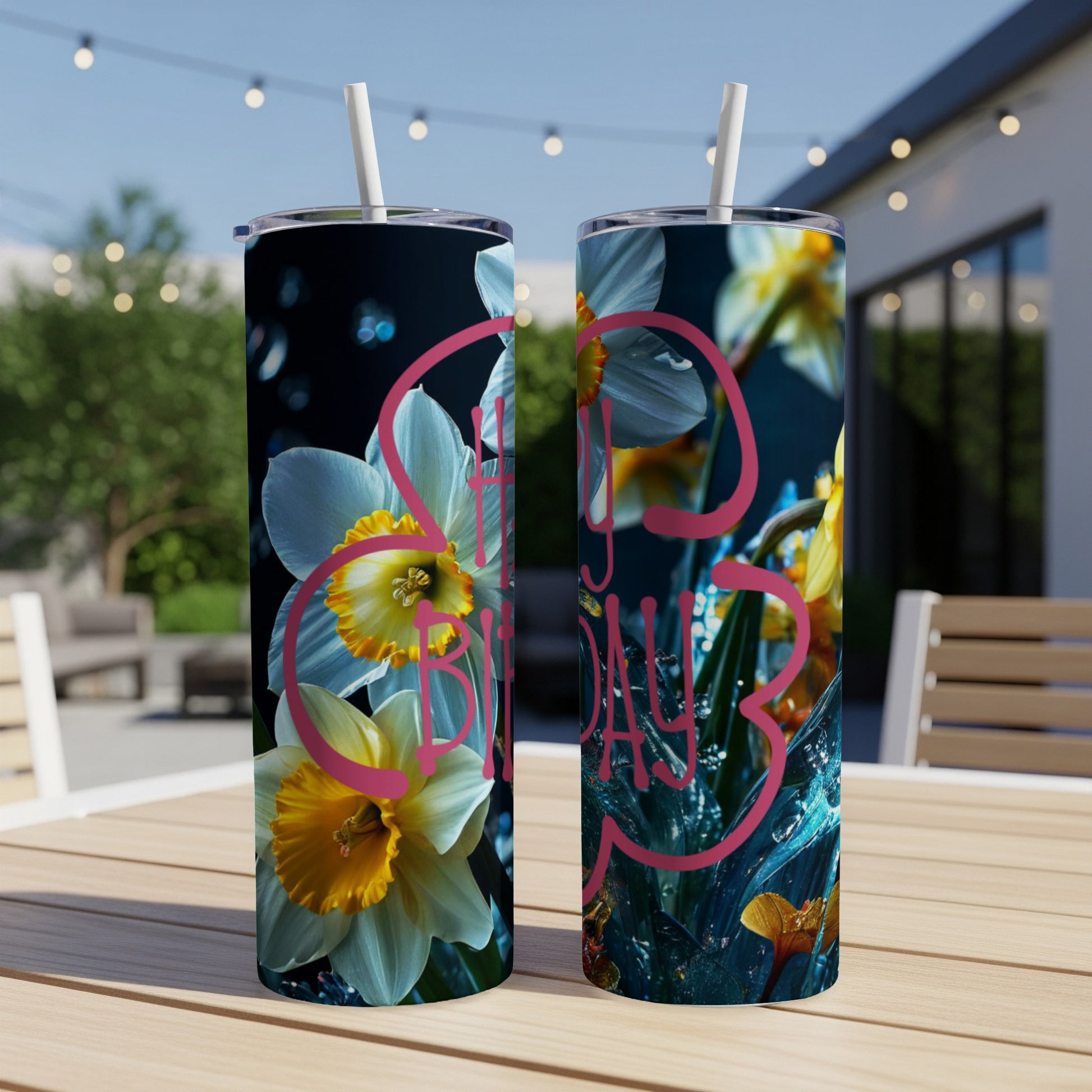 Two white tumblers with a floral and "Happy Birthday" design on a table.