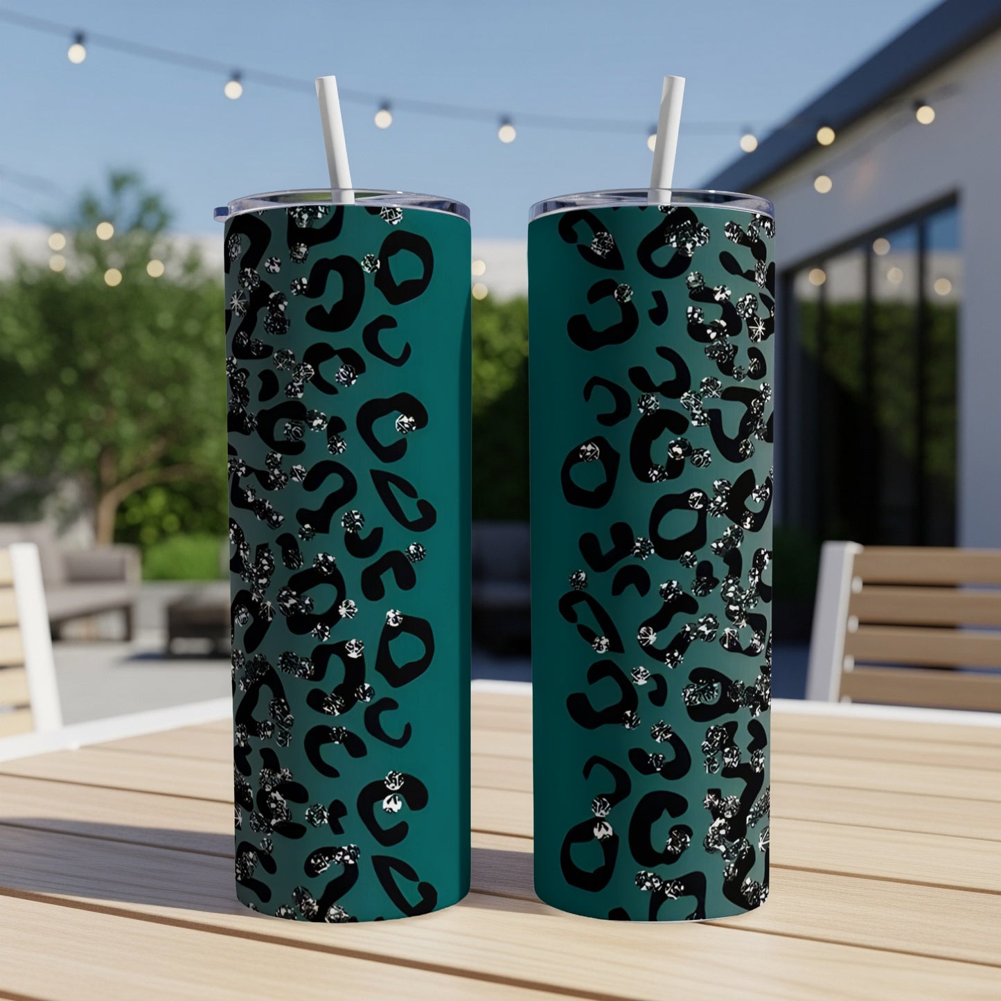 Two teal tumblers with a black and silver leopard print design sit on a table.
