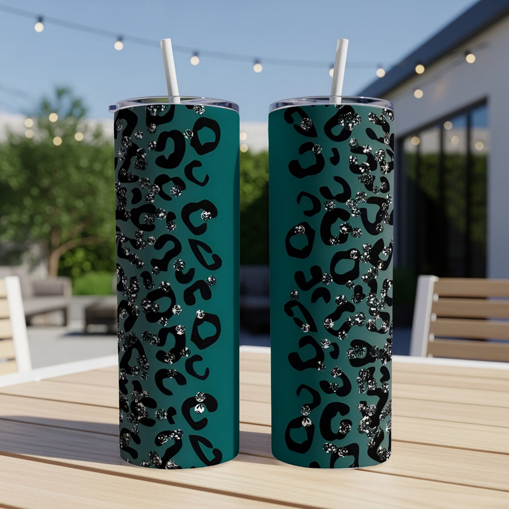 Two teal tumblers with a black and silver leopard print design sit on a table.