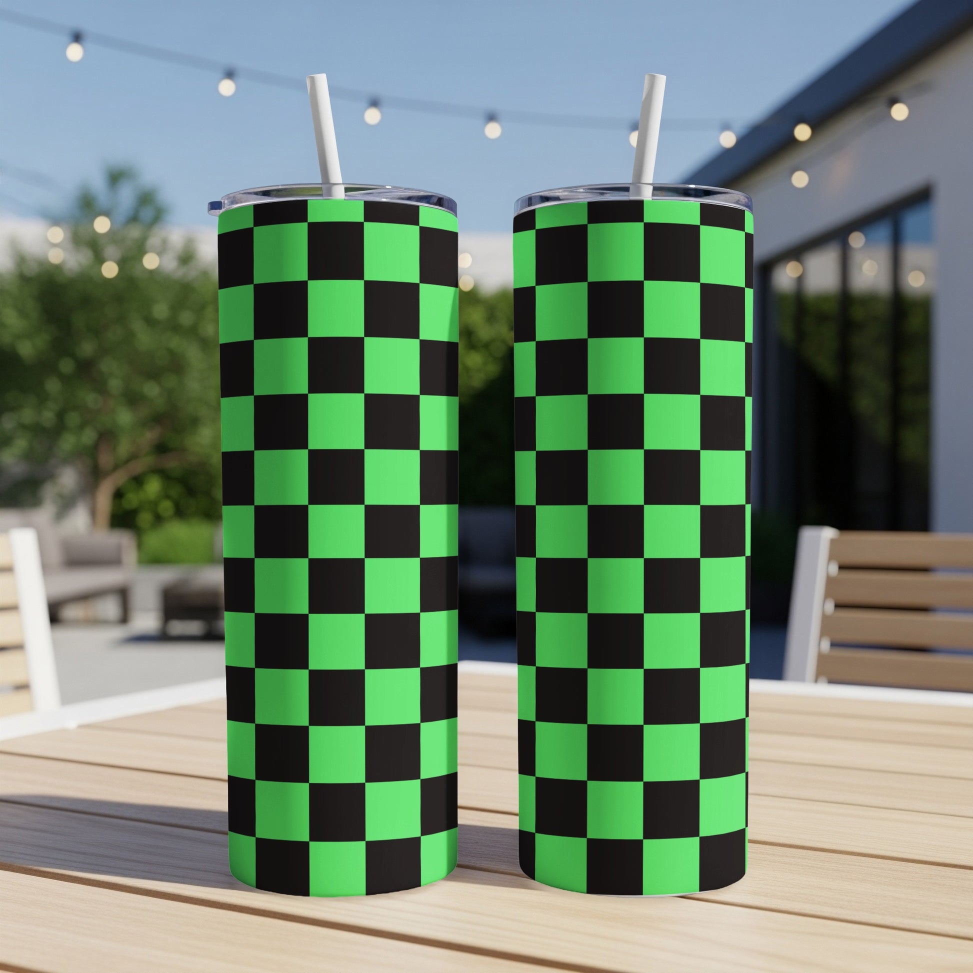 Two green and black checkered tumblers with straws on a table.