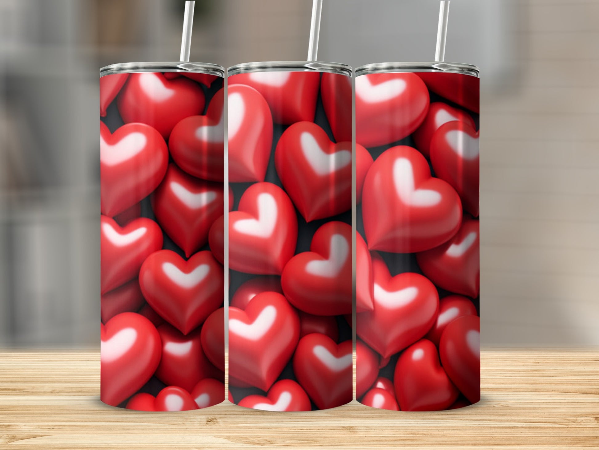 Three tumblers with a pattern of red hearts on a wooden surface.