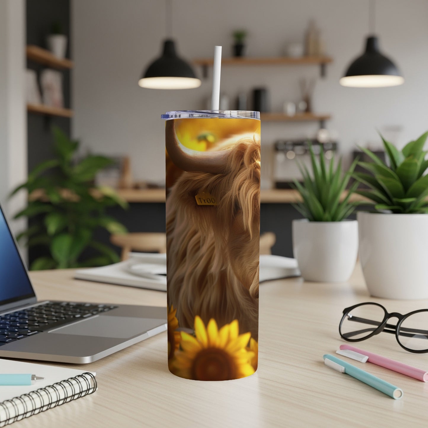 Highland cow with sunflowers on a tumbler on a desk.