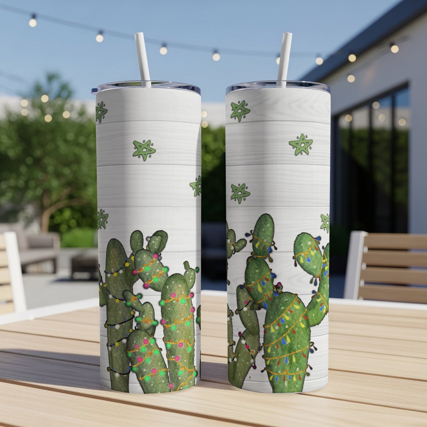 Two tumblers with cactus and Christmas lights design on a wooden table.
