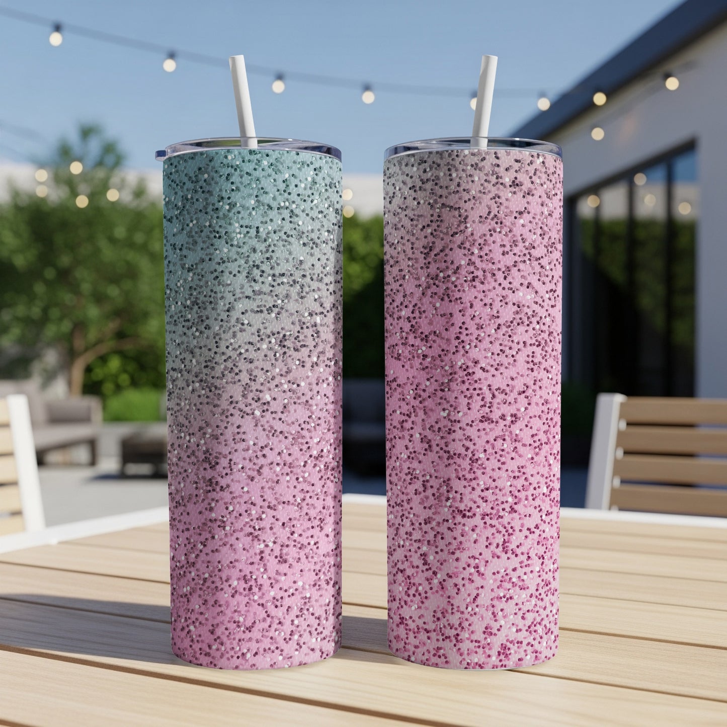 Two glitter tumblers, one blue-green, one pink, on a wooden table.