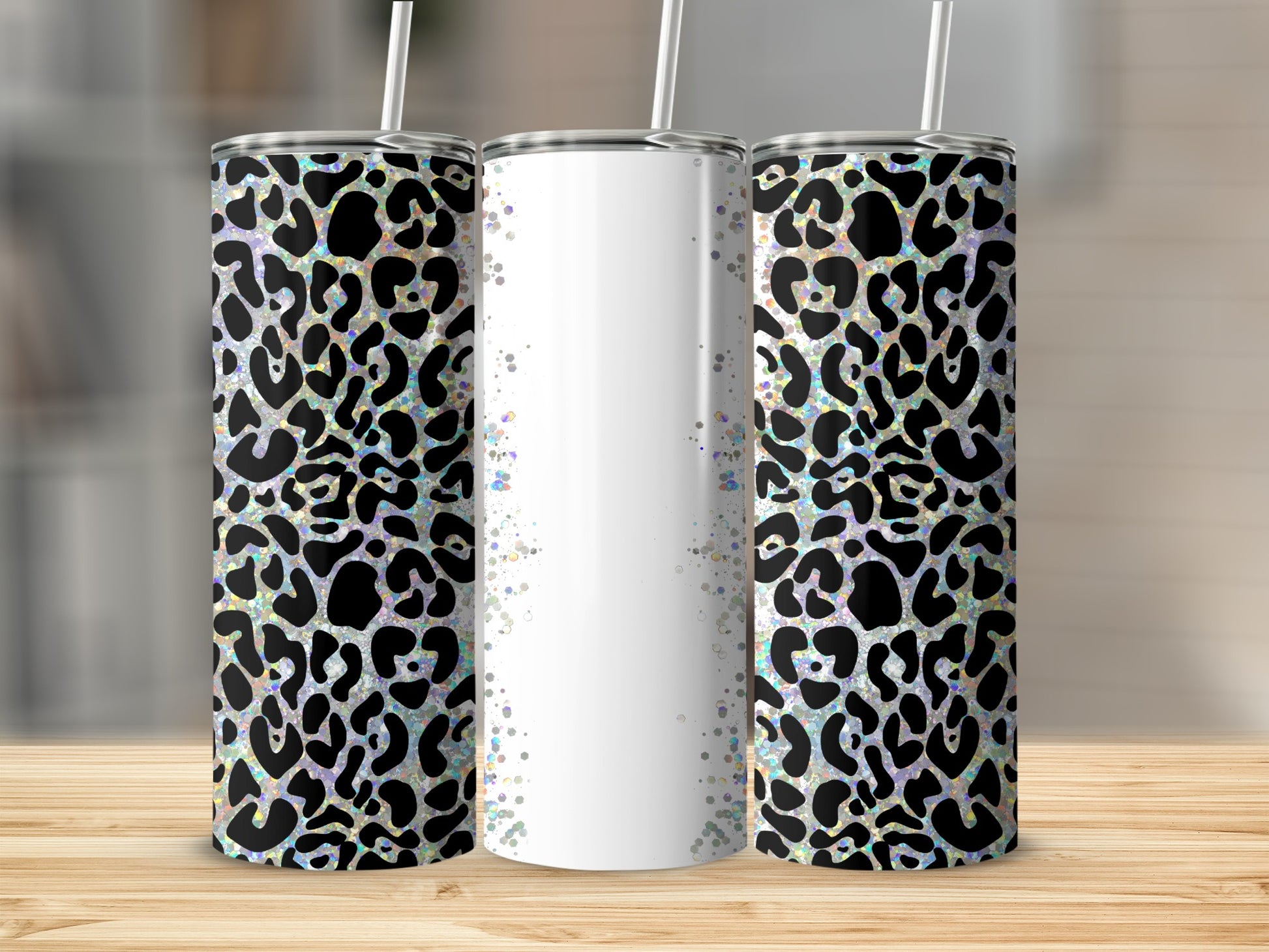 Three tumblers with leopard print and glitter designs on a wooden surface.