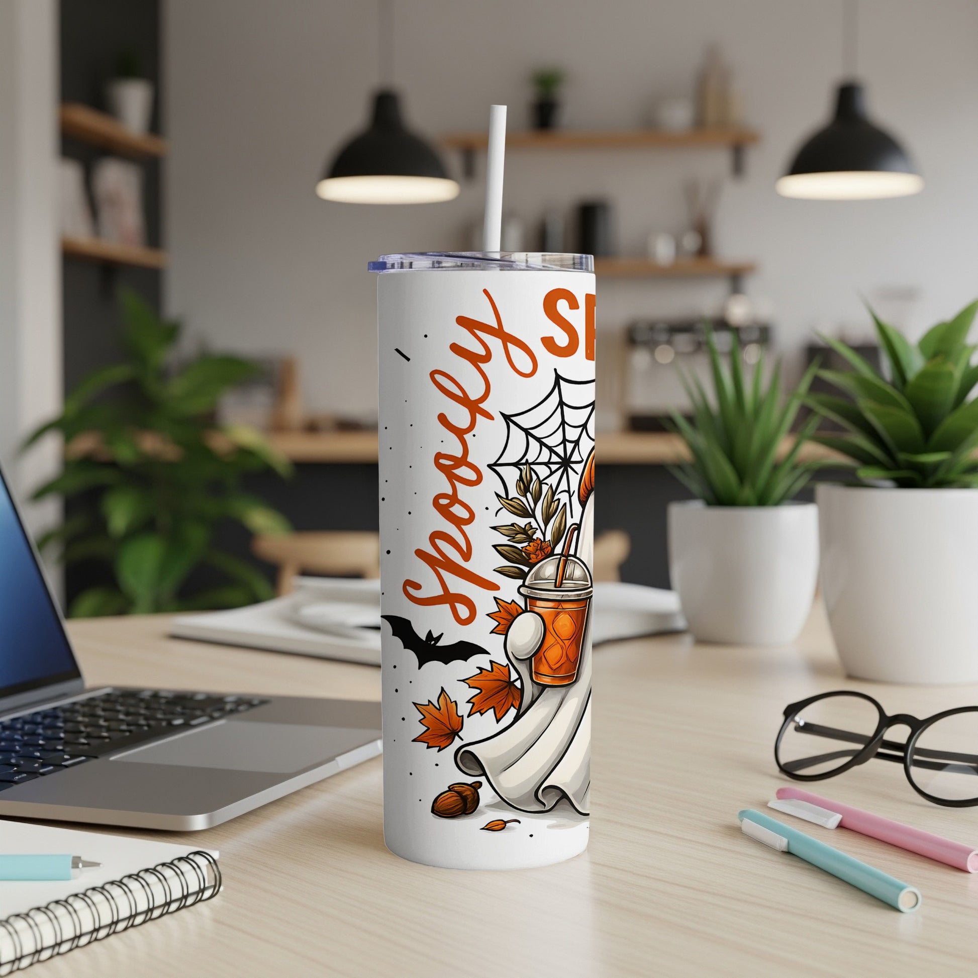 White tumbler with "Spooky Sippin'" text, ghost, pumpkin drink, bat, and autumn leaves.