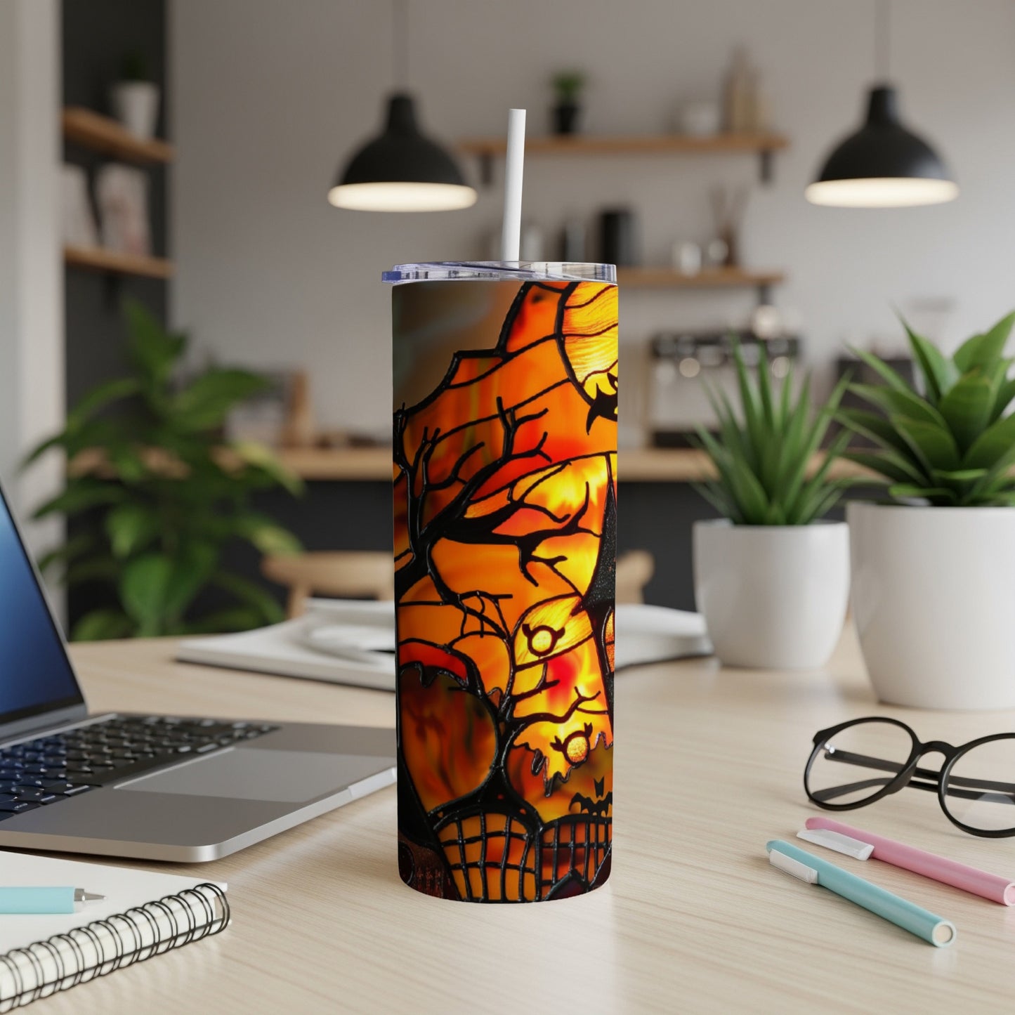 Halloween tumbler with spooky scene and straw on a desk.