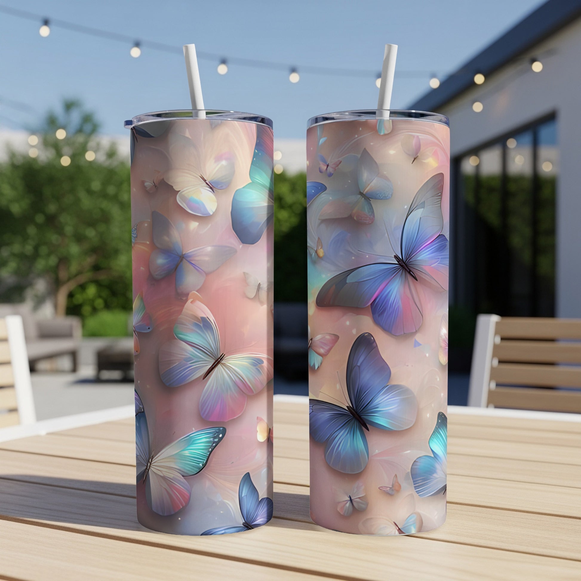 Two tall tumblers with a pastel butterfly design sit on a wooden table outdoors.