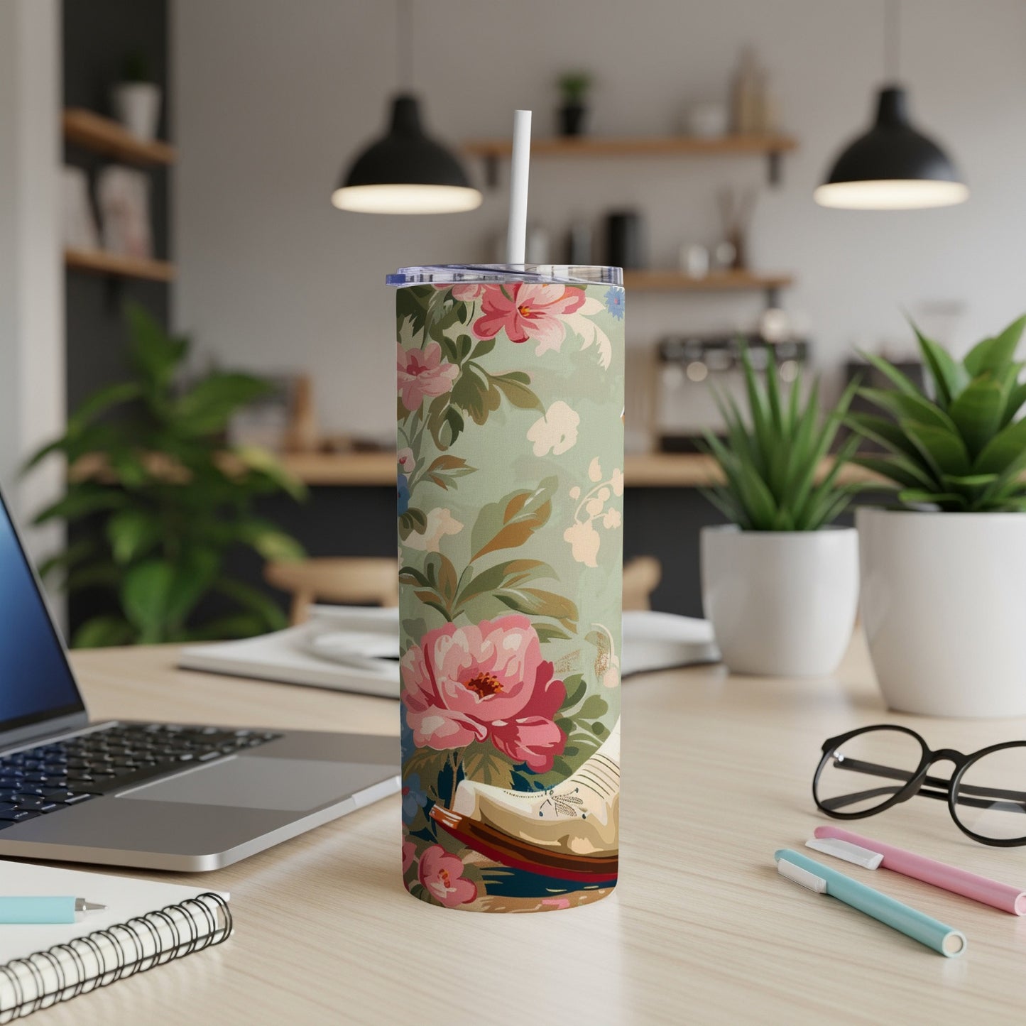 Floral tumbler with a straw on a desk next to a laptop.