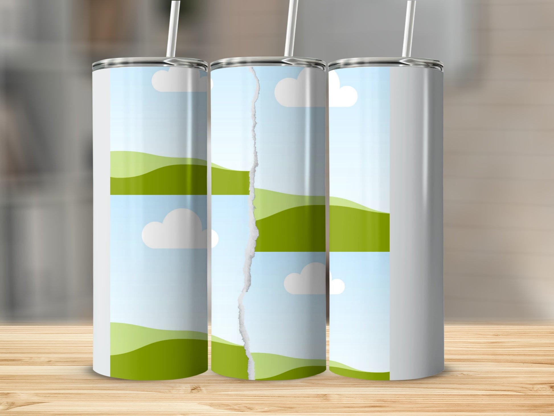 Three tumblers with a torn landscape graphic on a wooden surface.