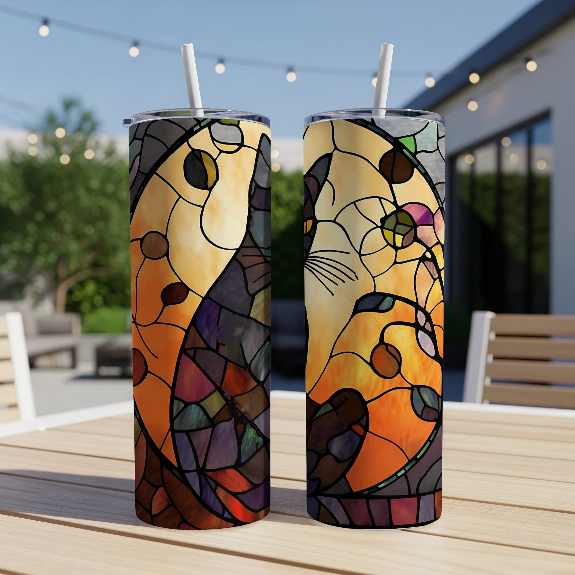 Two tall tumblers with stained-glass cat yin-yang design on patio table.