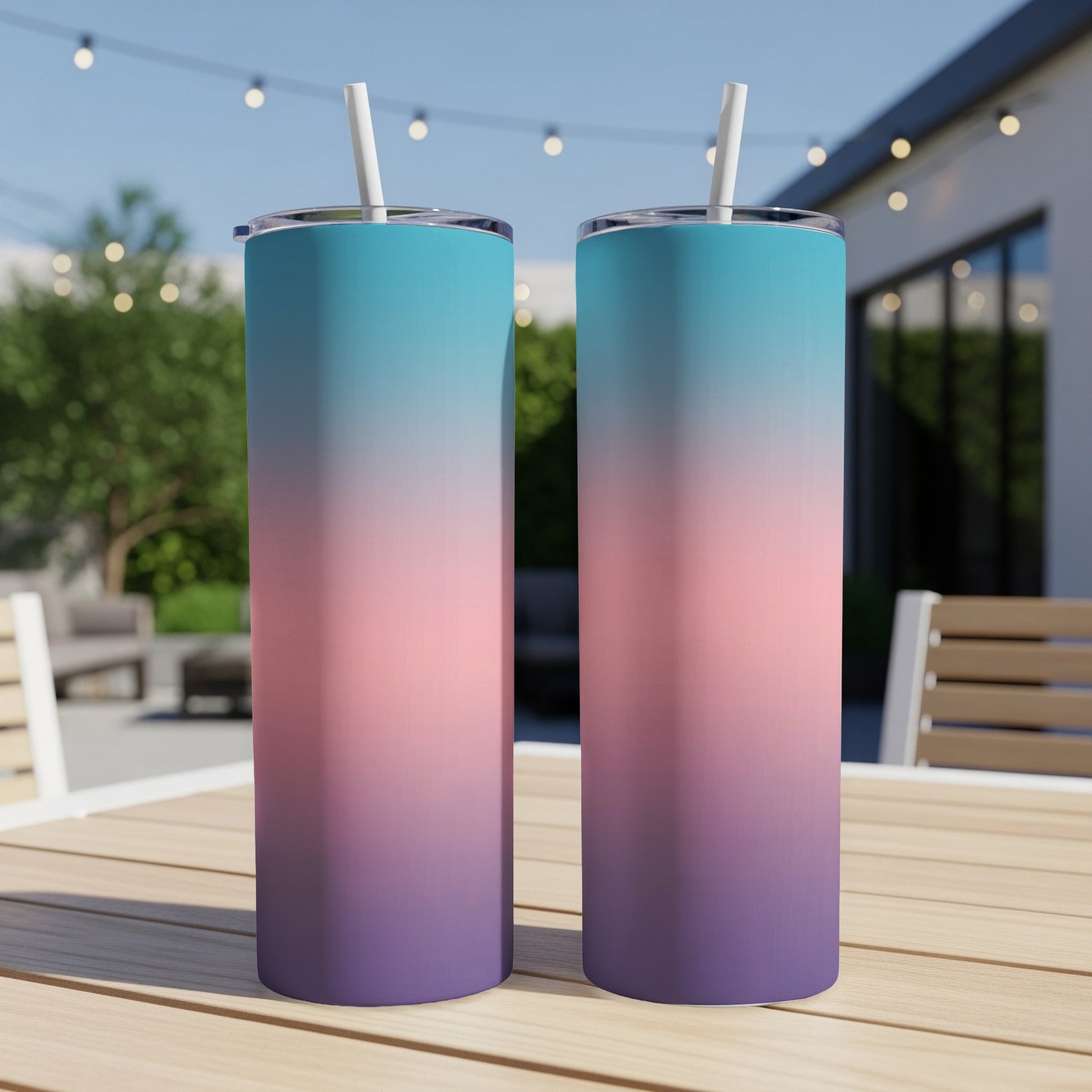 Two tumblers with a gradient of blue, pink, and purple sit on a wooden table.