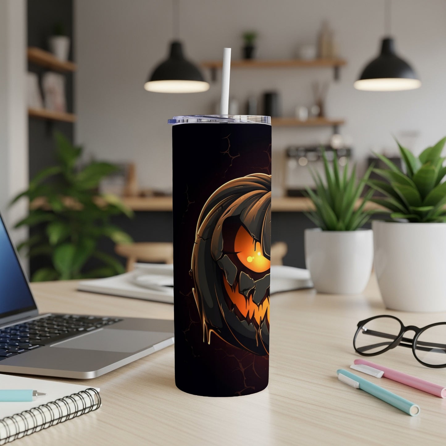 Black tumbler with a cracked jack-o'-lantern design and a white straw.