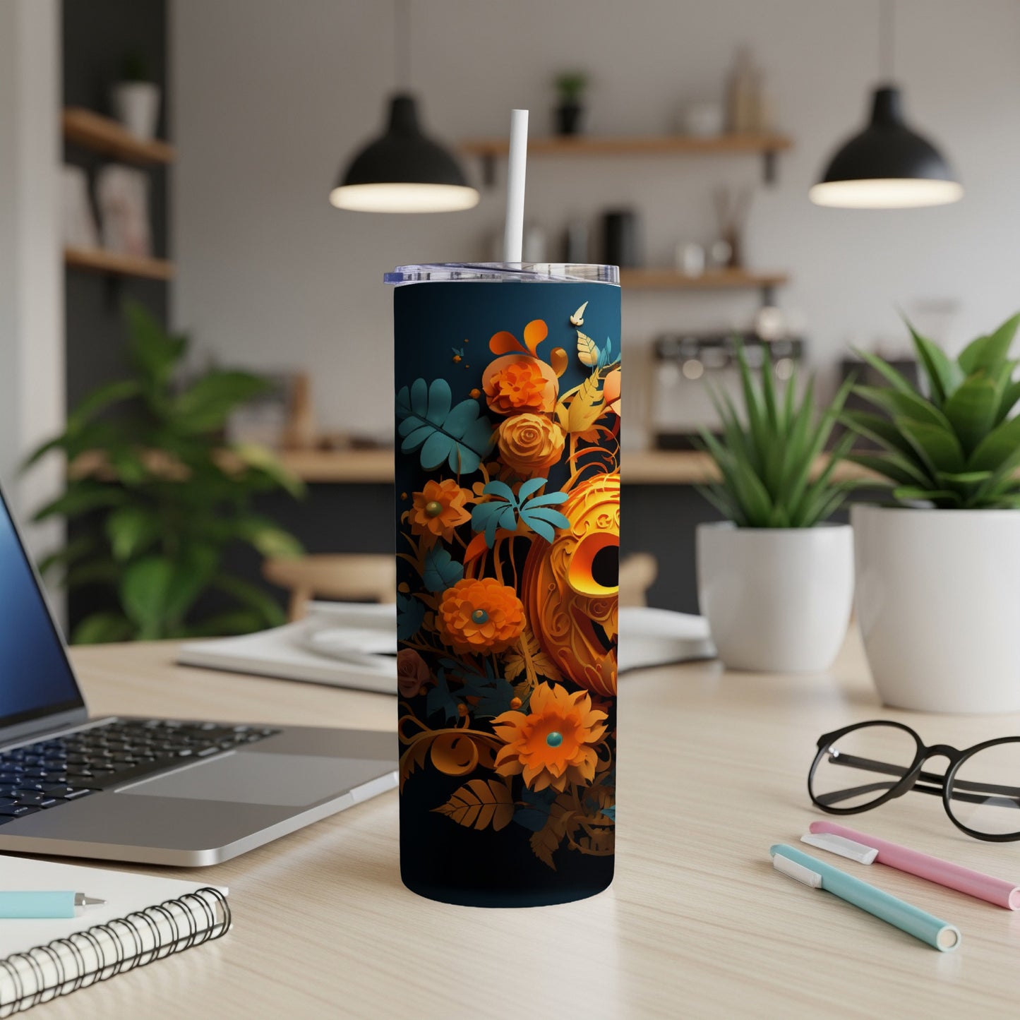 Dark tumbler with orange floral and jack-o'-lantern design, straw inserted.
