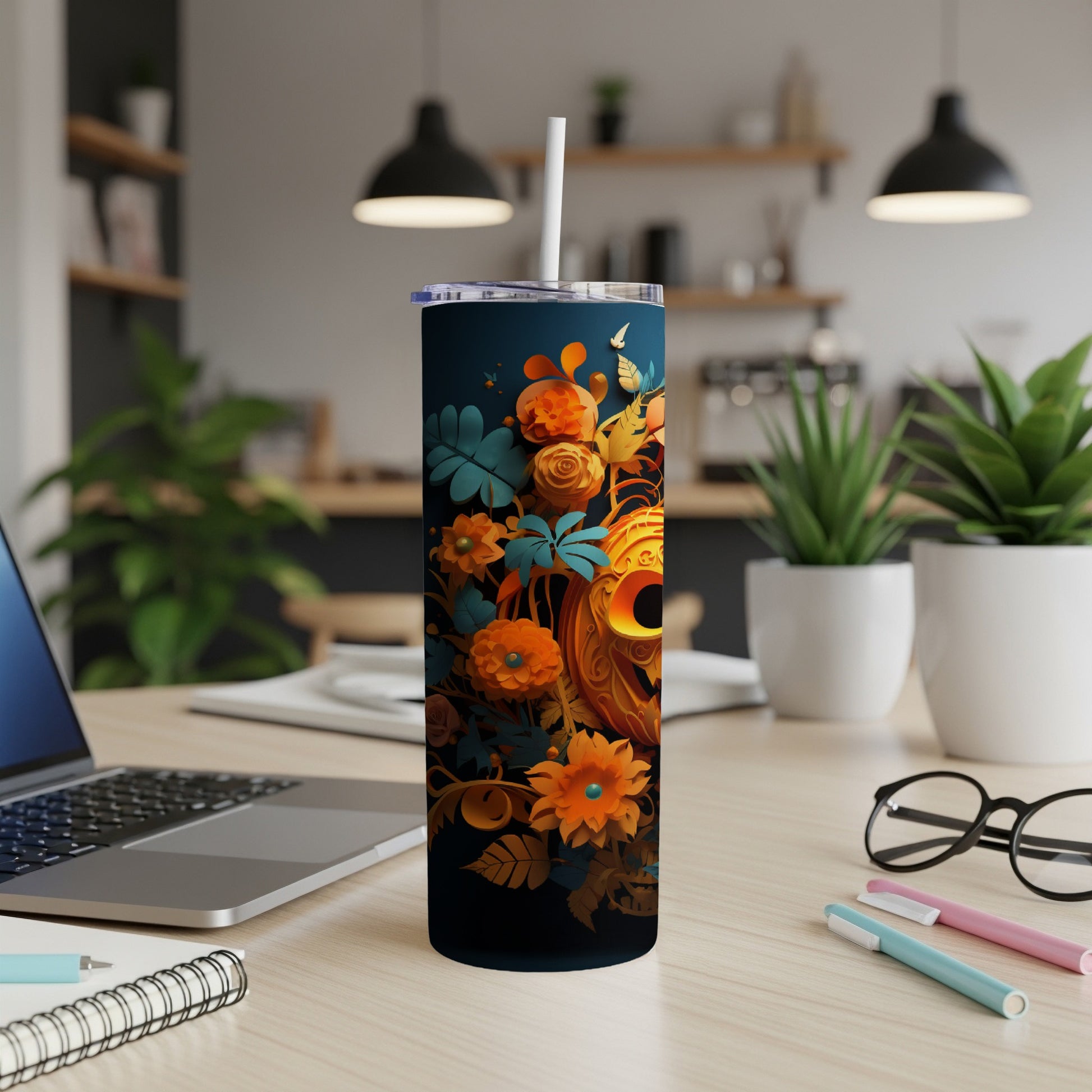 Dark tumbler with orange floral and jack-o'-lantern design, straw inserted.