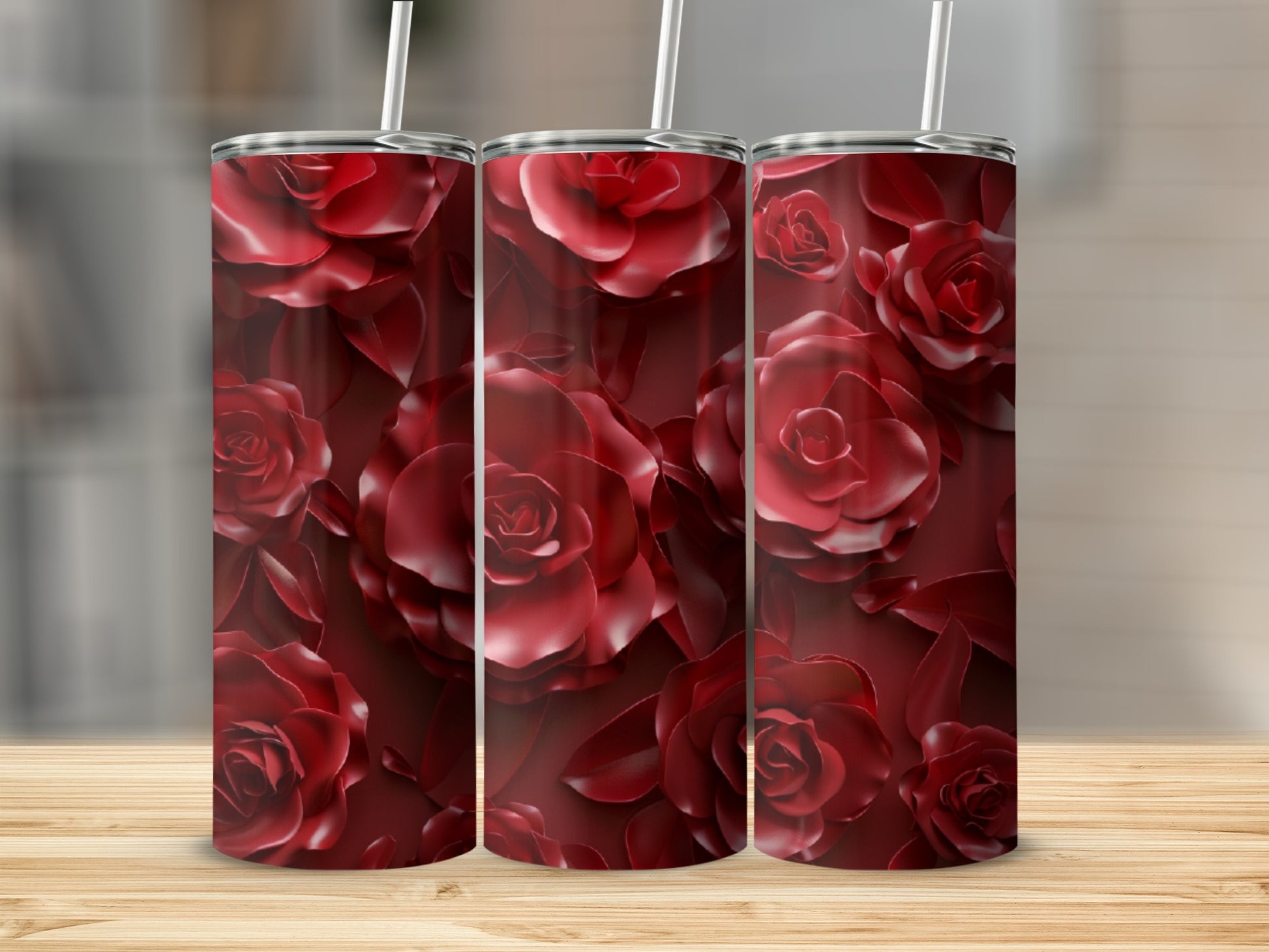 Three red rose tumblers with a floral pattern on a wooden surface.