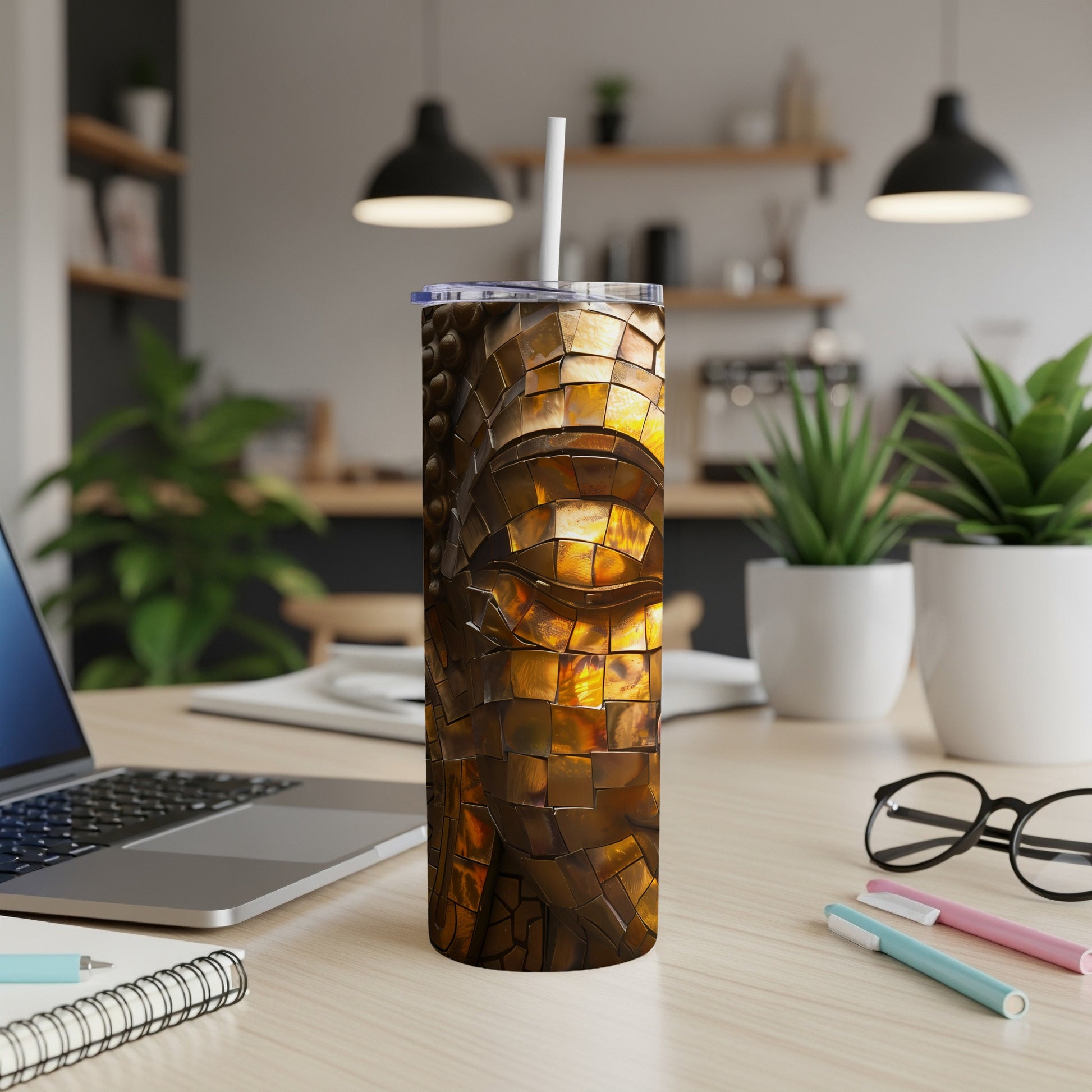 Gold mosaic pattern tumbler with a straw on a wooden desk.