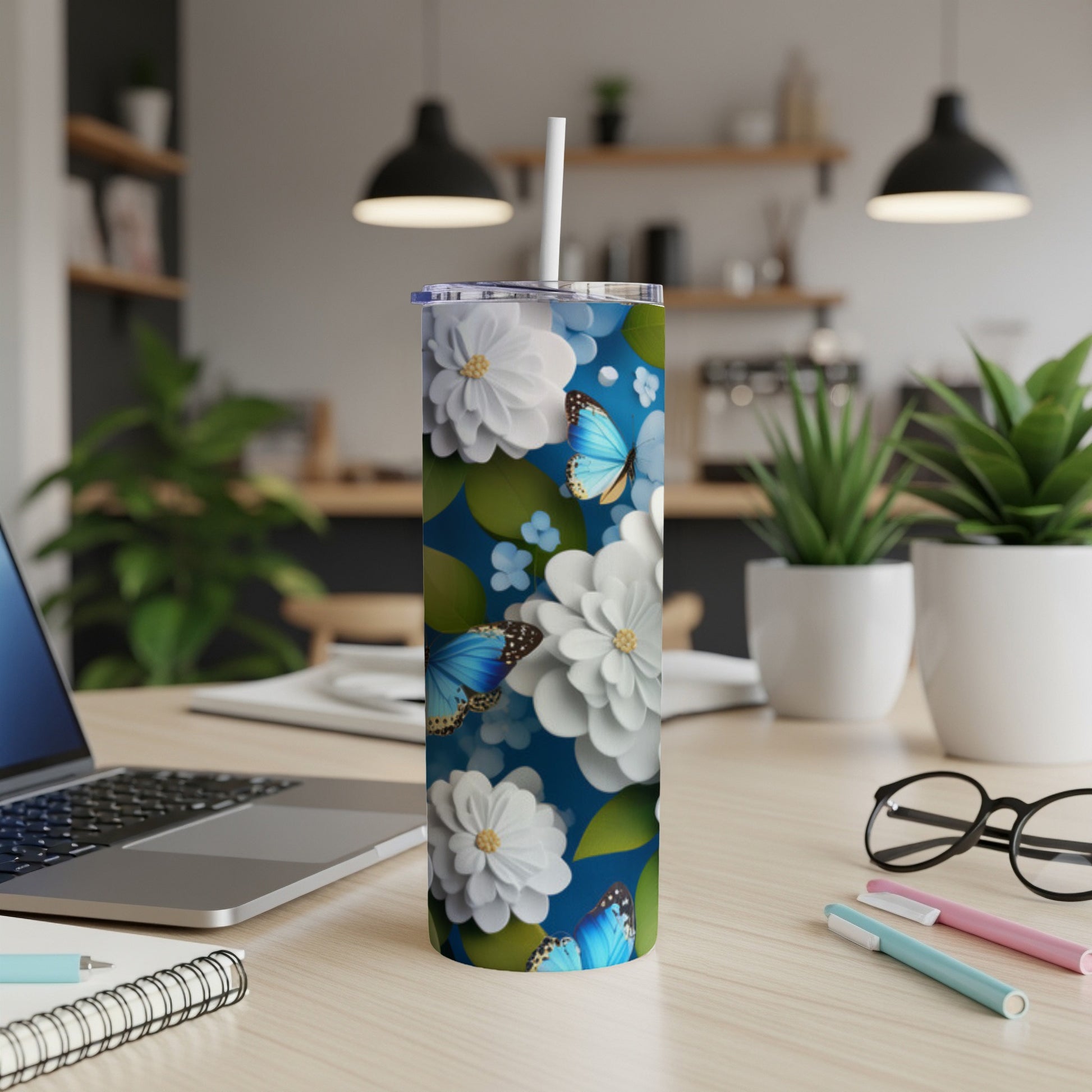 White tumbler with blue butterflies and white flowers on a desk.