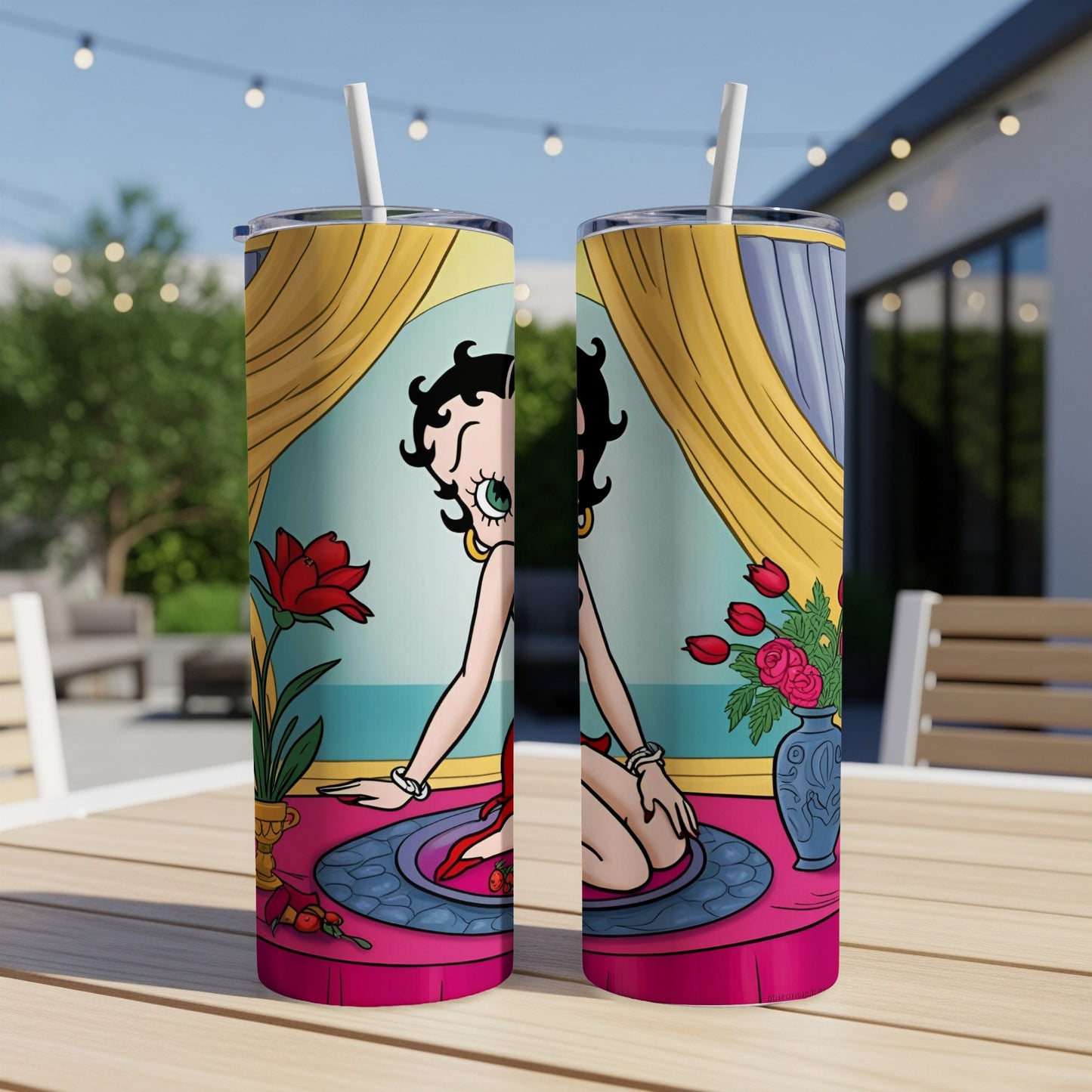 Two Betty Boop tumblers with red flowers and a blue vase on a table.