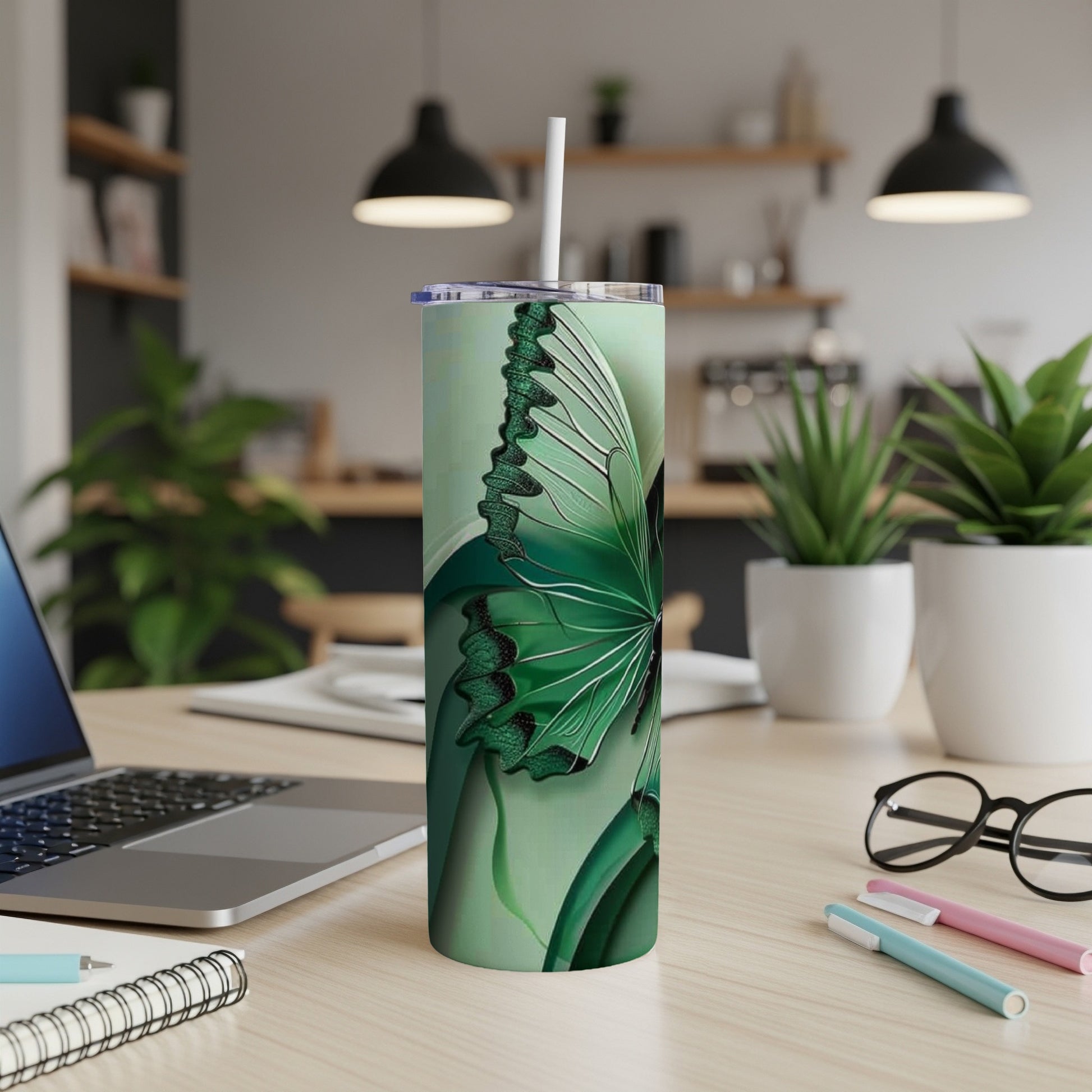 Green butterfly tumbler with straw on desk.