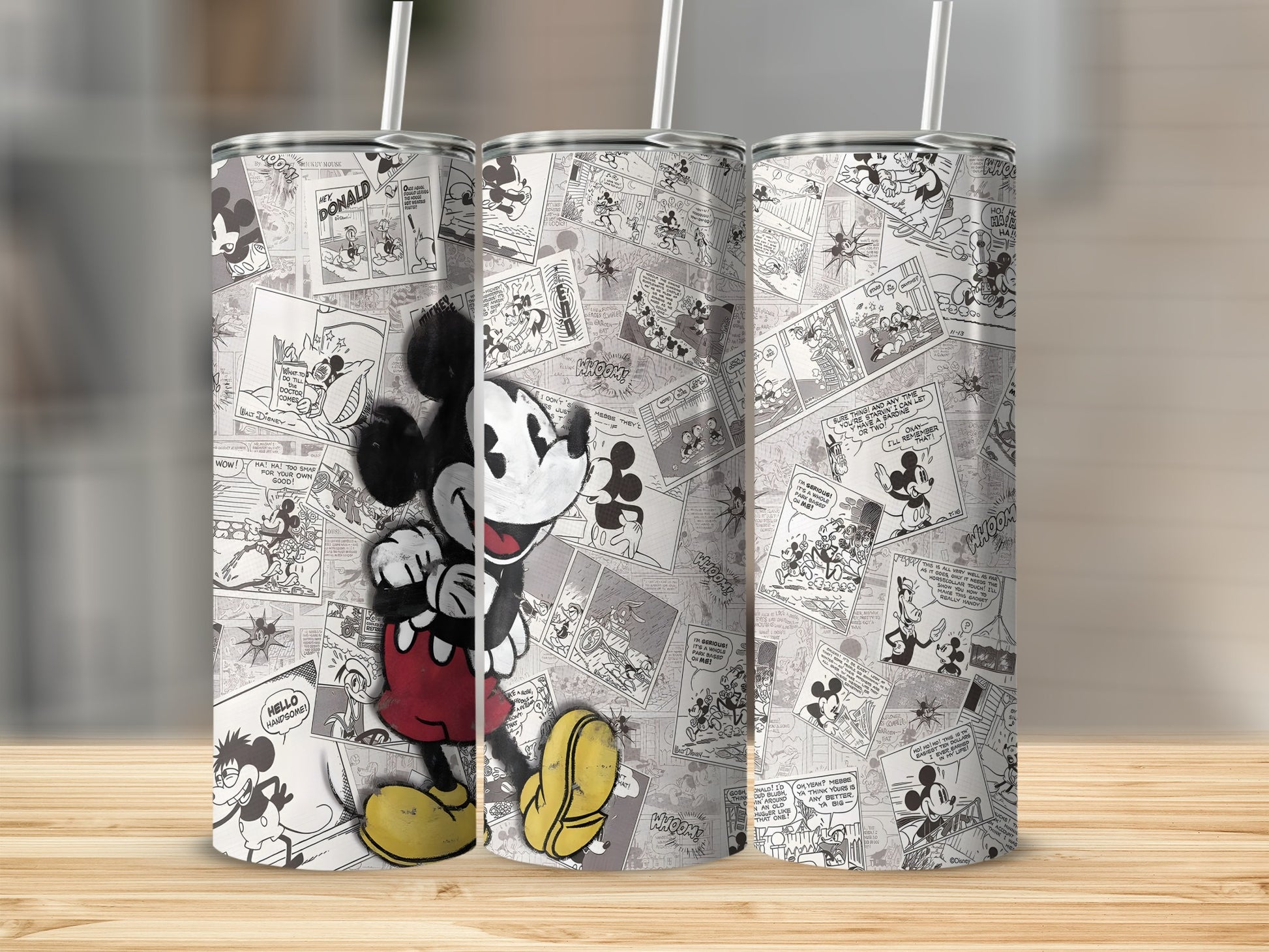 Mickey Mouse comic strip tumbler with straw on a wooden surface.