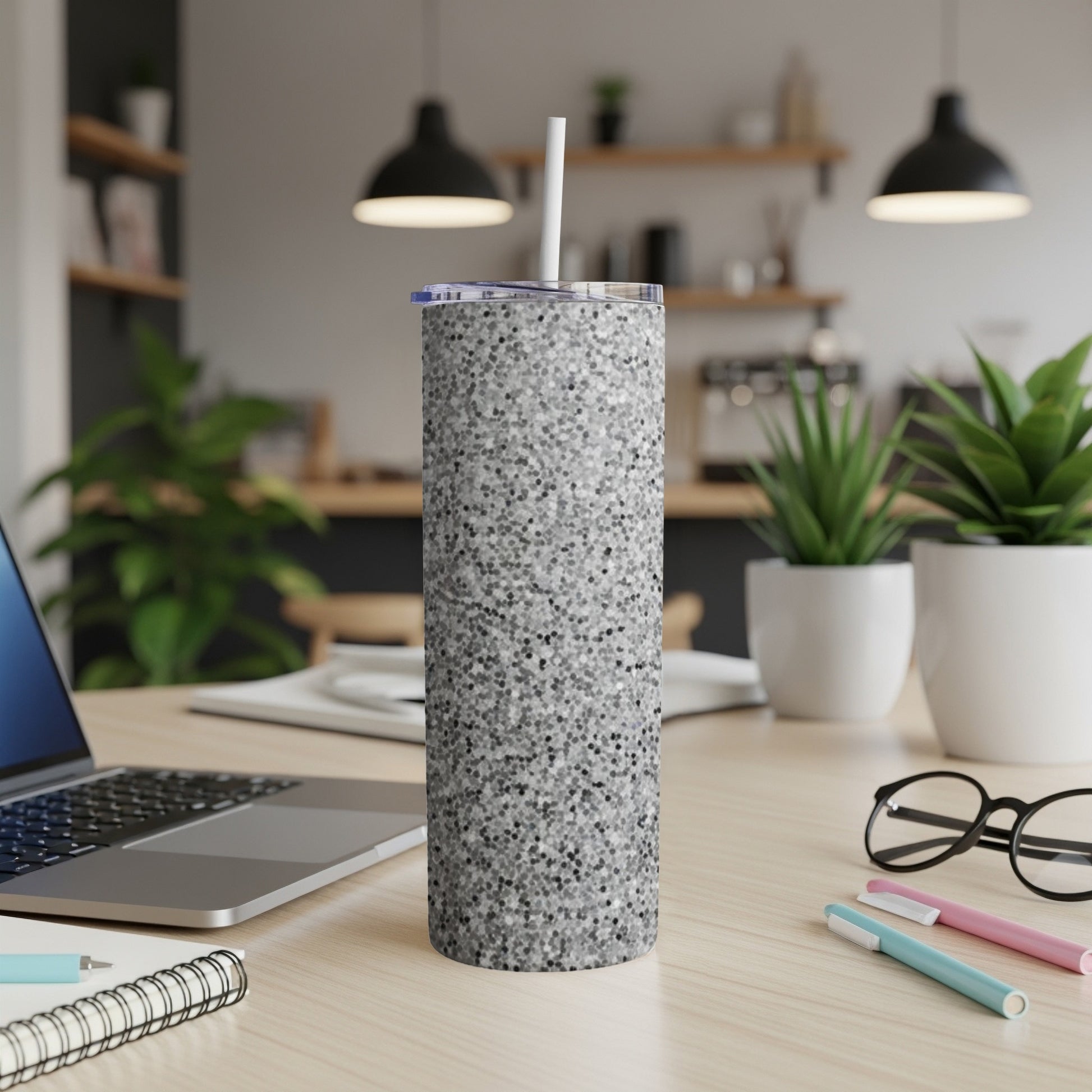 Silver glitter tumbler with a white straw on a desk.