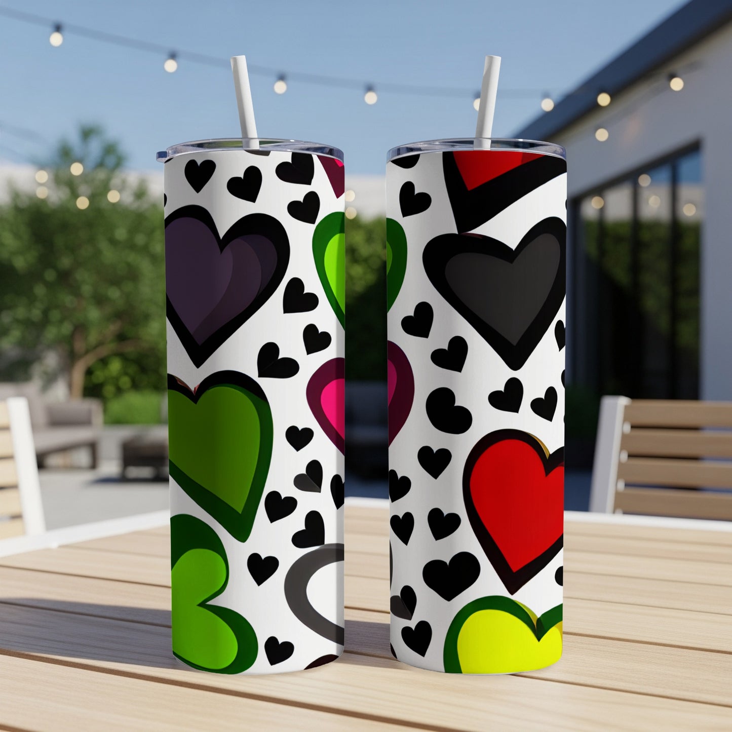 Two tumblers with a colorful heart pattern on a patio table.