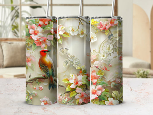 Tumbler with a bird on a branch with pink and white flowers.
