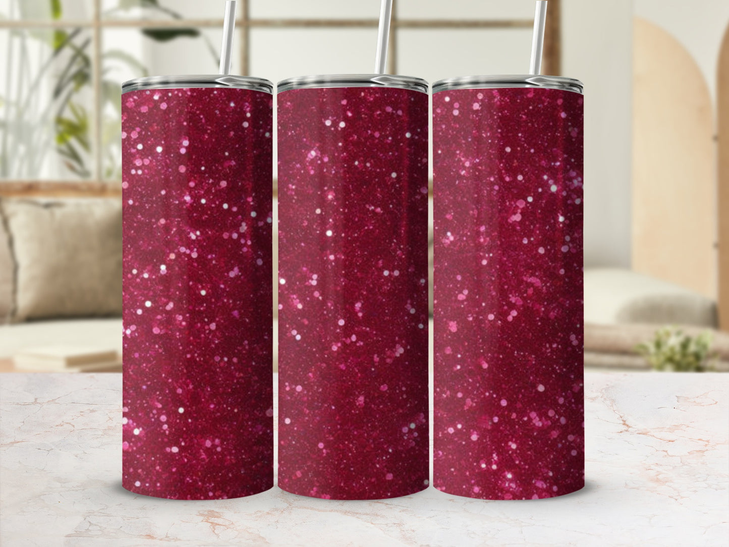 Three glitter tumblers with straws on a marble surface.