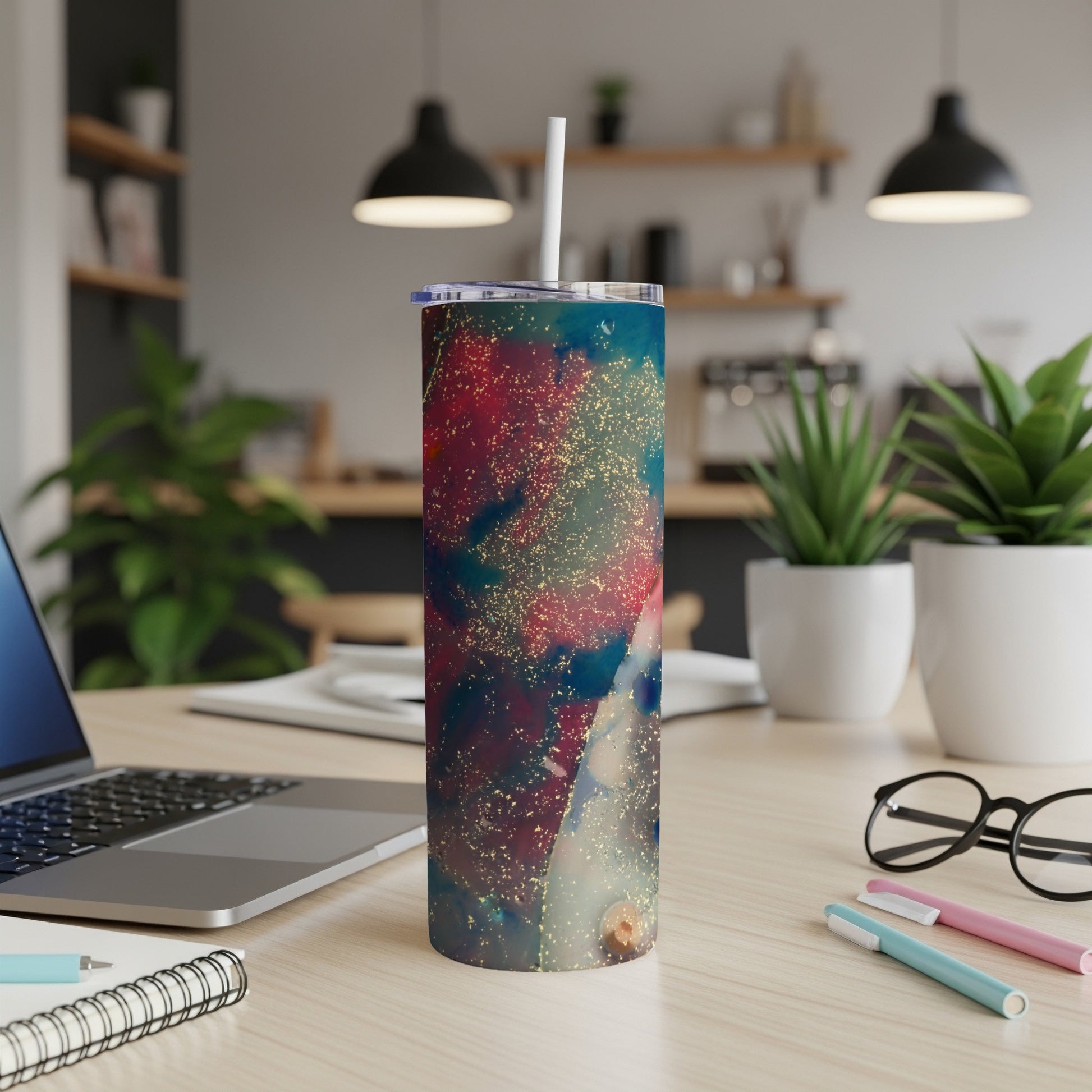 Tumbler with galaxy-like pattern and straw on a desk.