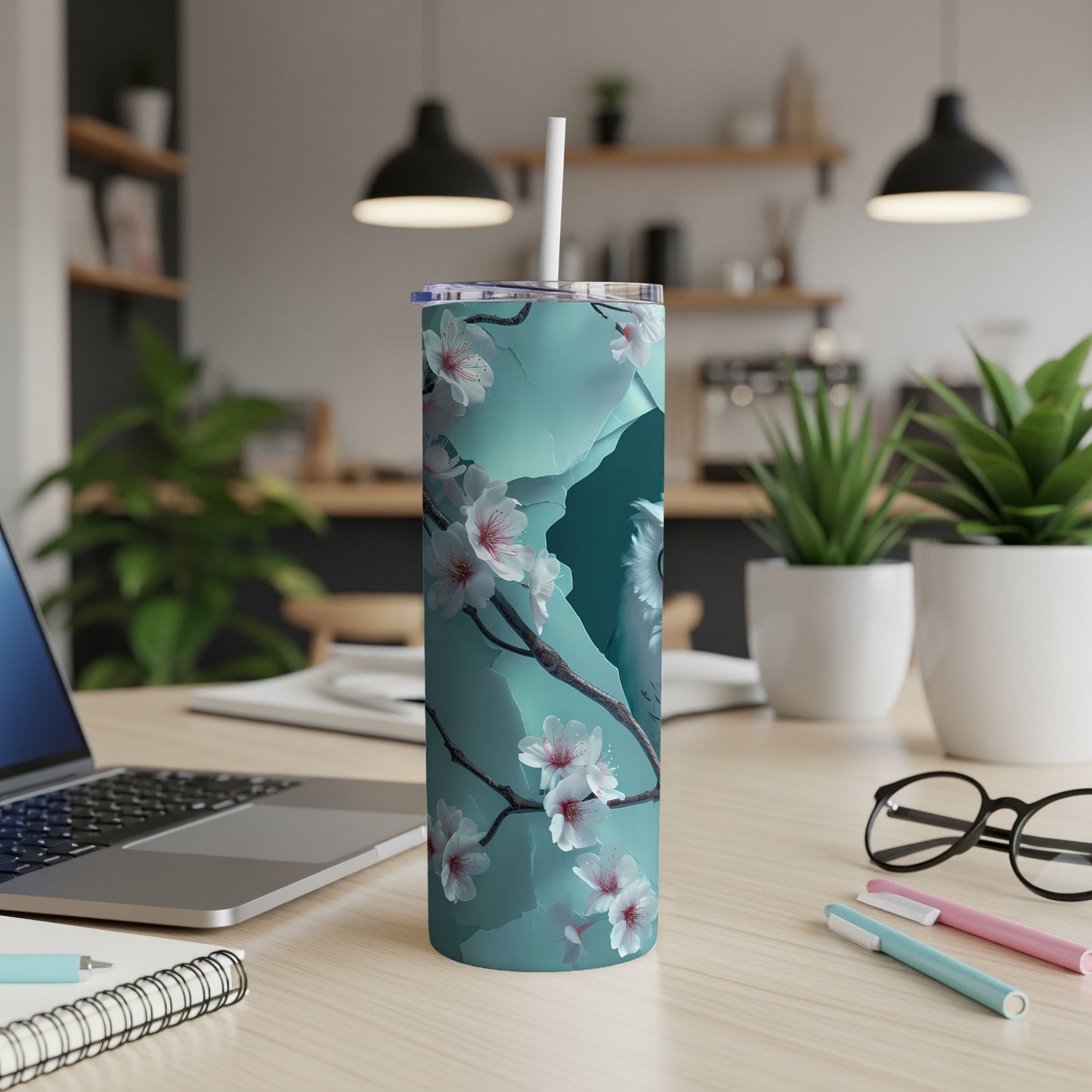 Teal tumbler with cherry blossoms, white straw, on a desk.