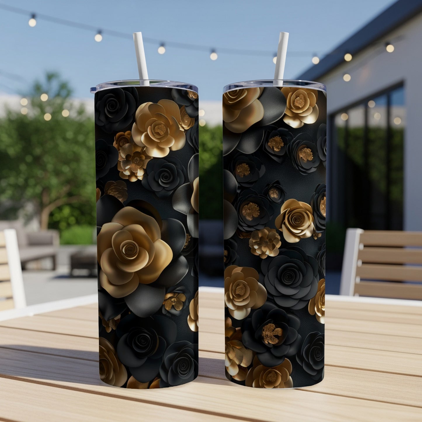 Two black tumblers with gold and black floral patterns sit on a table outdoors.
