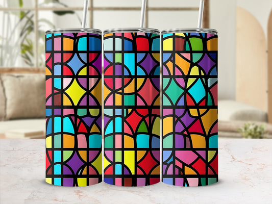 Three stained glass tumblers with colorful geometric patterns on a marble surface.
