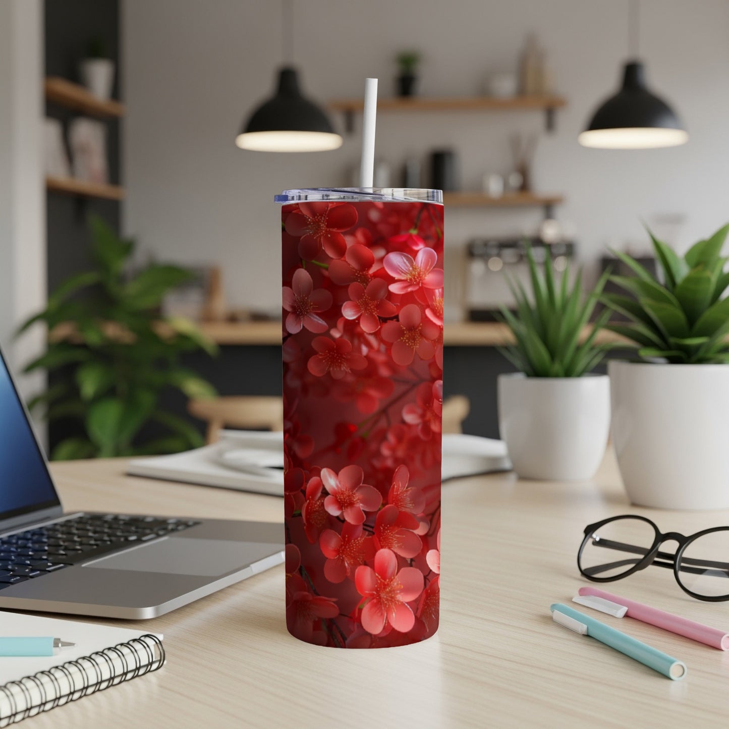 Red cherry blossoms on a dark background cover a slim tumbler with a straw.