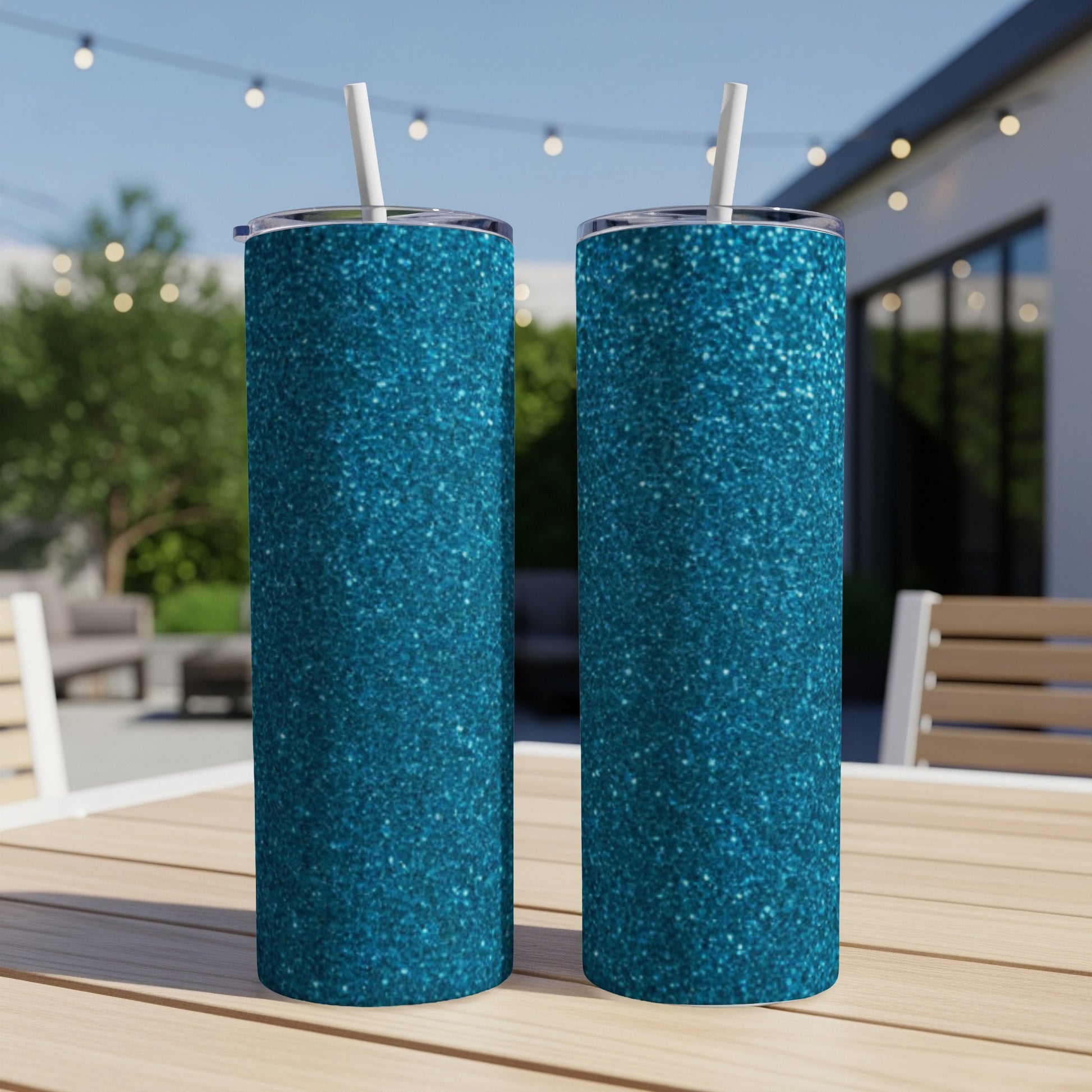 Two teal glitter tumblers with white straws on a wooden table.