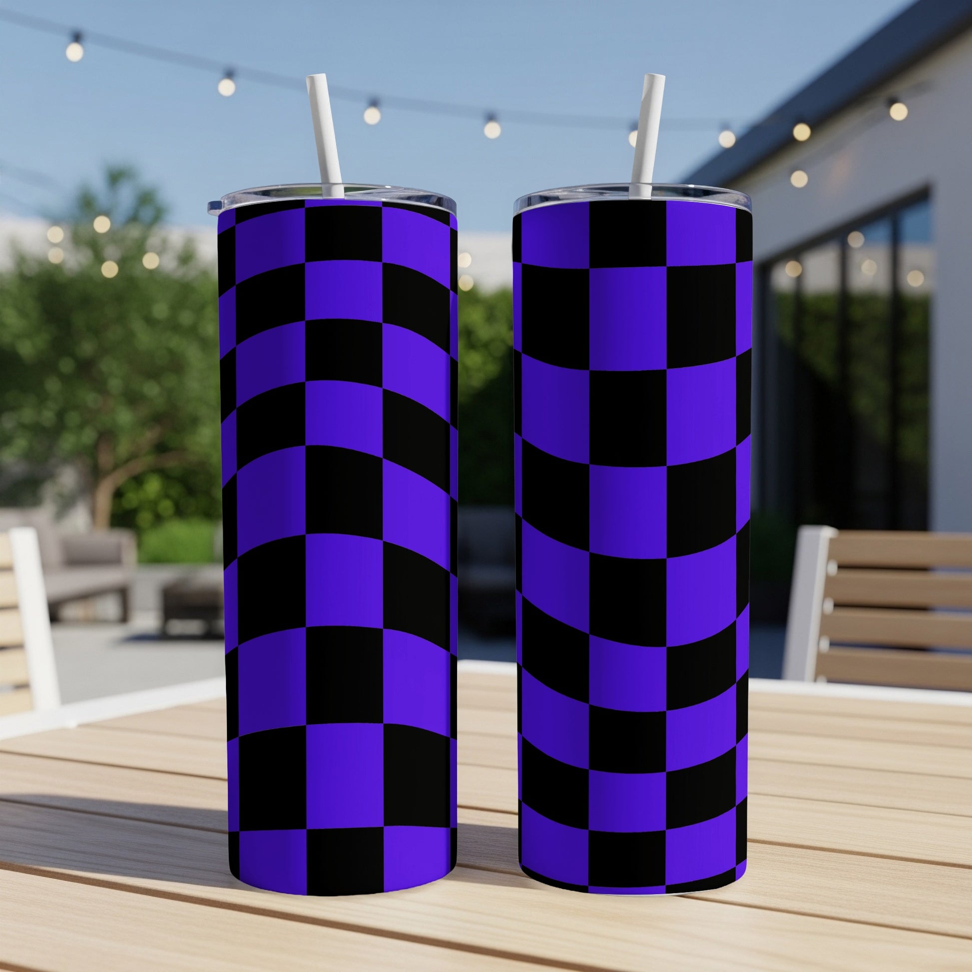 Two tall purple and black checkered tumblers with straws on a table.