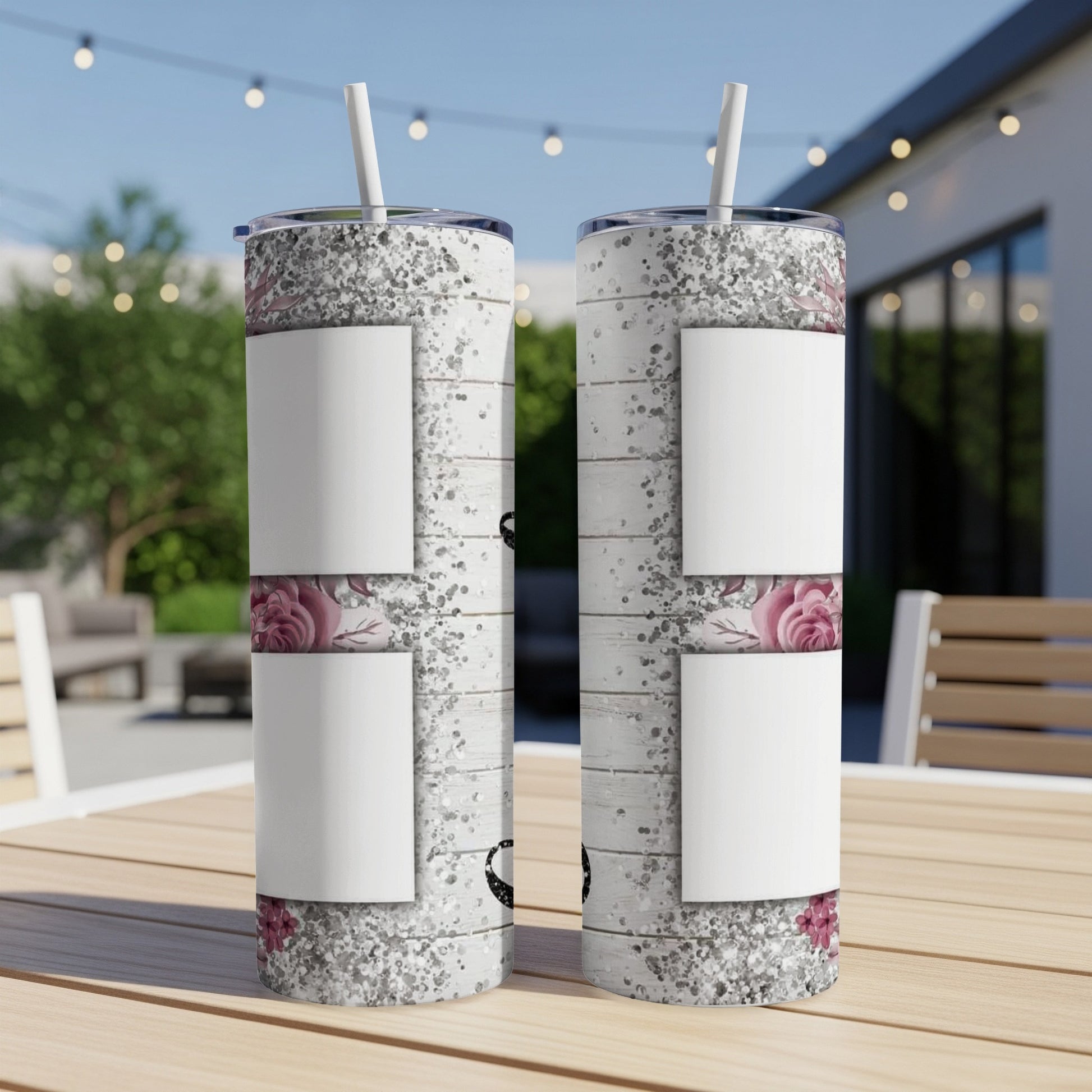 Two white tumblers with floral and glitter design and white straws, on a table.