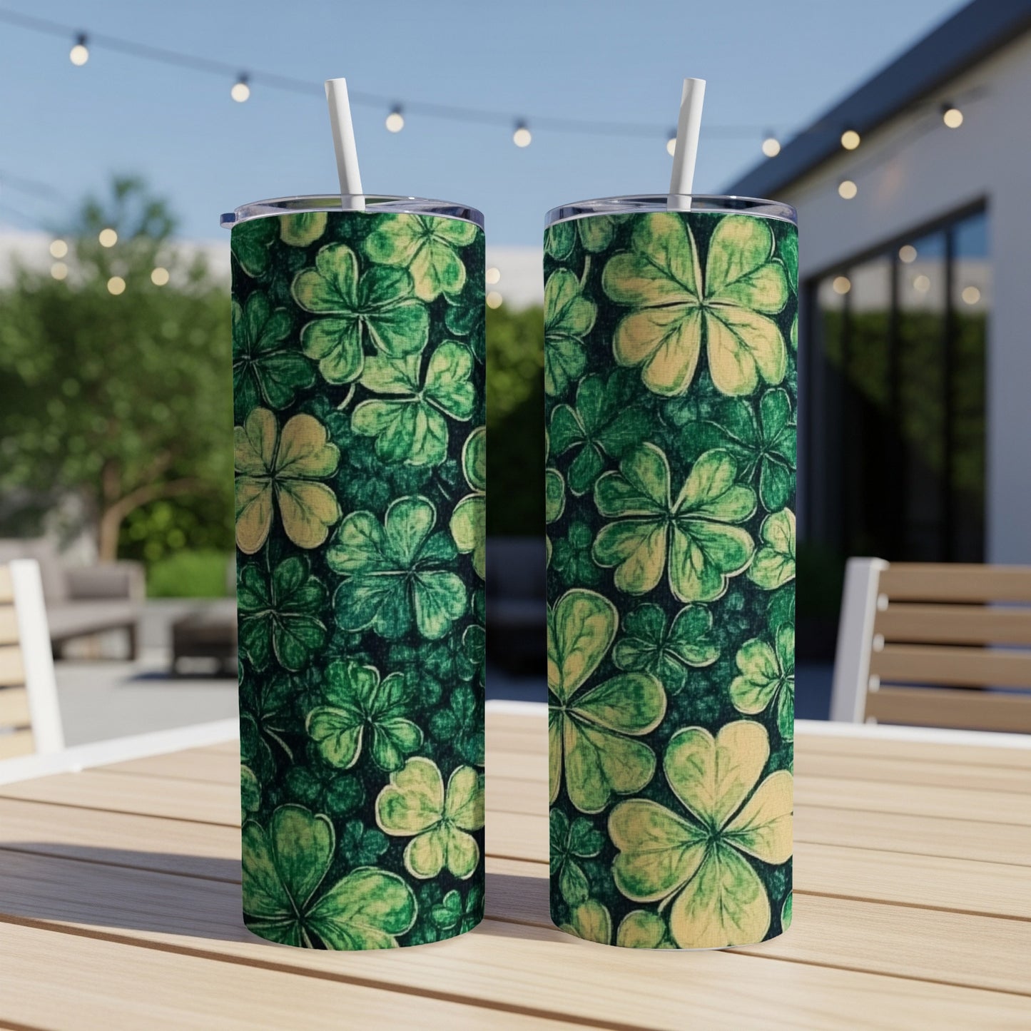 Two green shamrock patterned tumblers with straws on a wooden table.