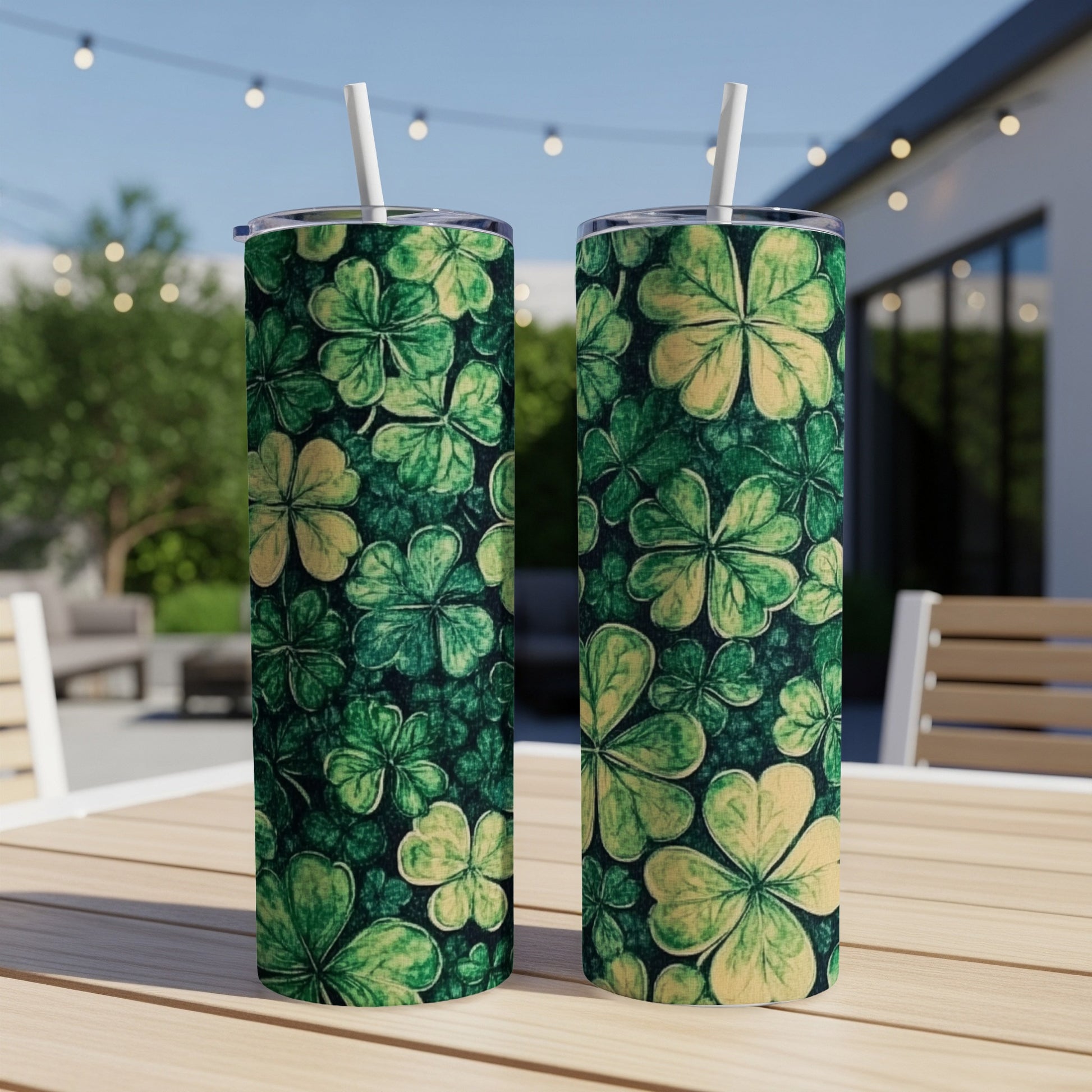 Two green shamrock patterned tumblers with straws on a wooden table.