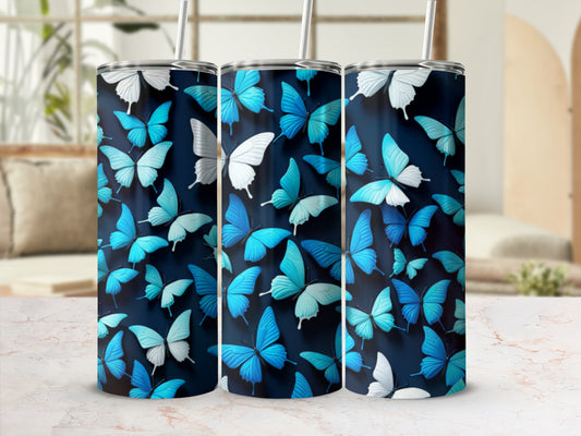Three blue butterfly pattern tumblers with straws on a marble surface.