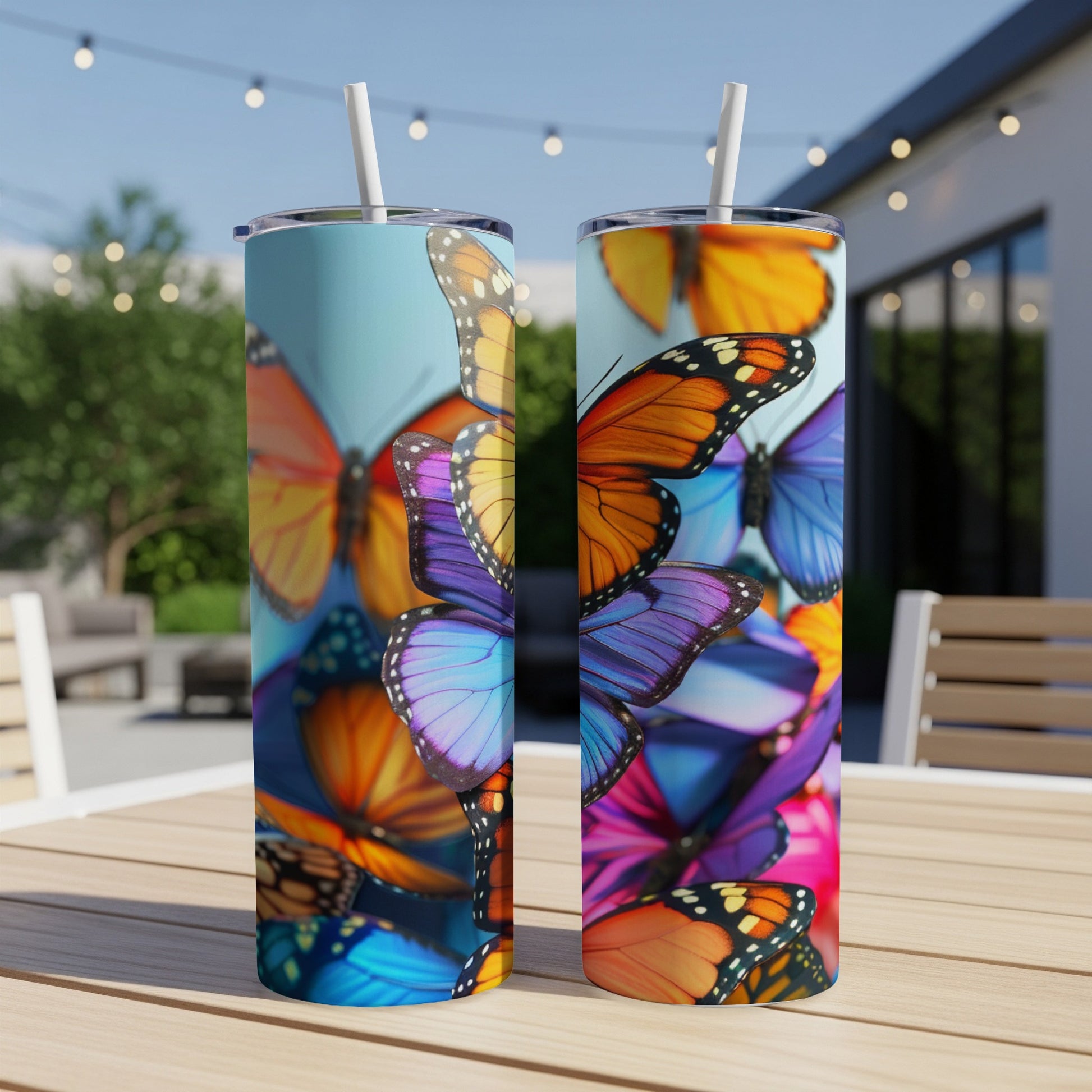 Two skinny tumblers with a colorful butterfly pattern on a wooden table.