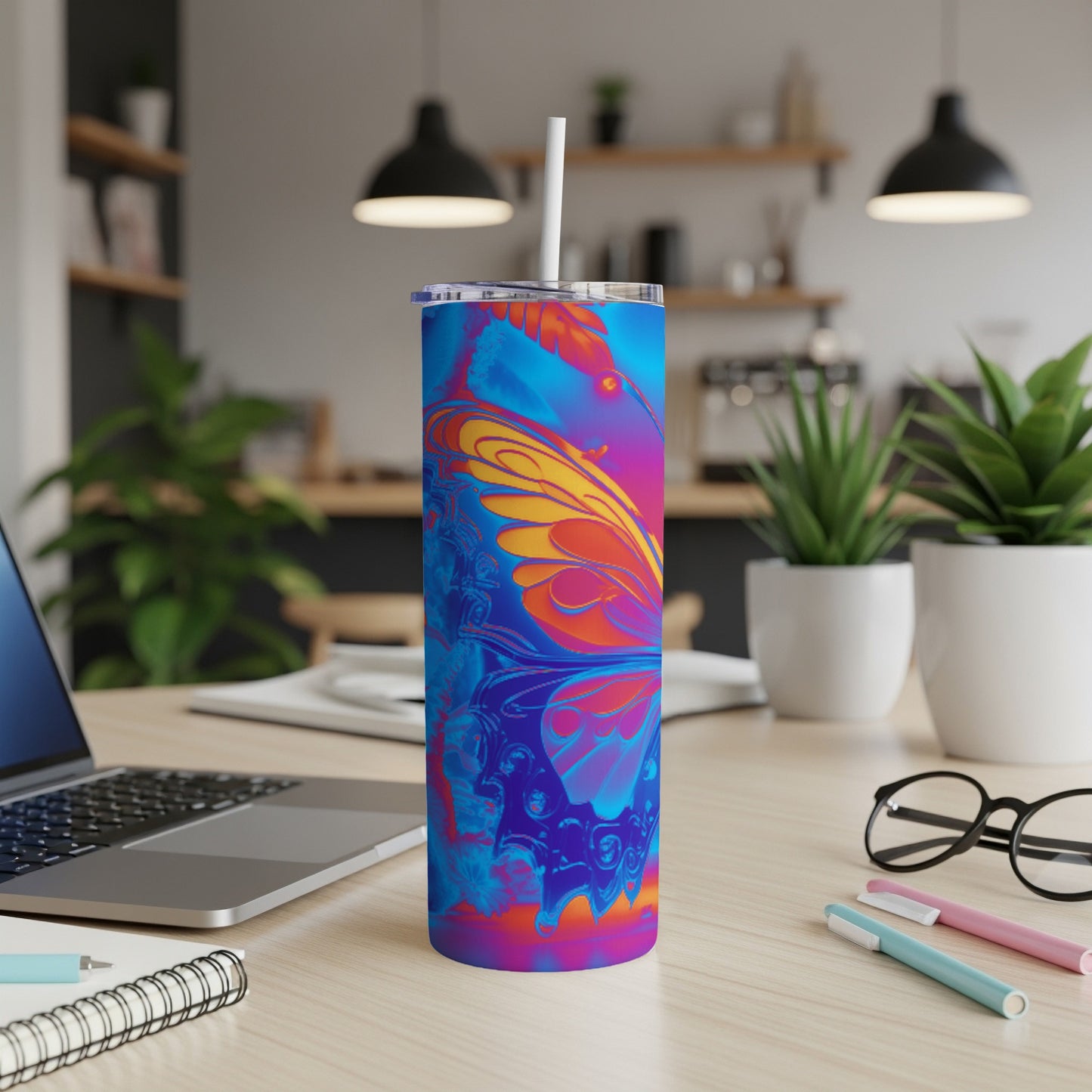 Blue and orange butterfly tumbler with straw on a desk.