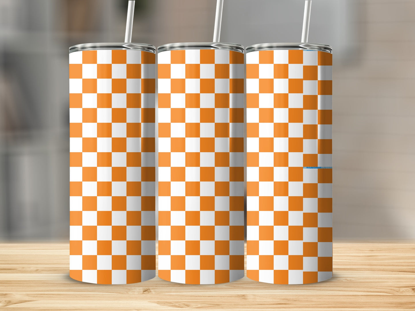 Three tumblers with orange and white checkered pattern on a wooden surface.