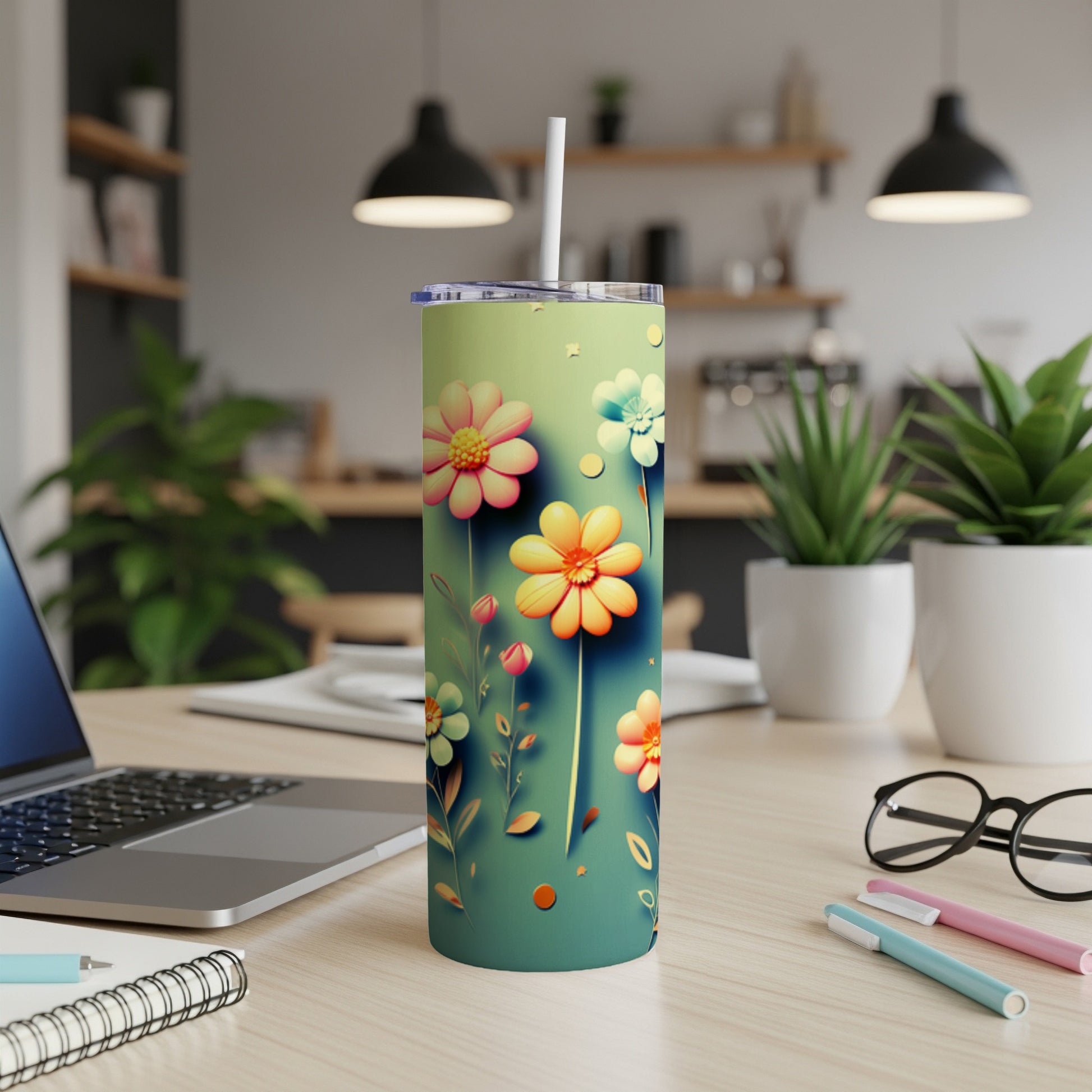 Tall tumbler with colorful cartoon flowers and a straw on a desk.