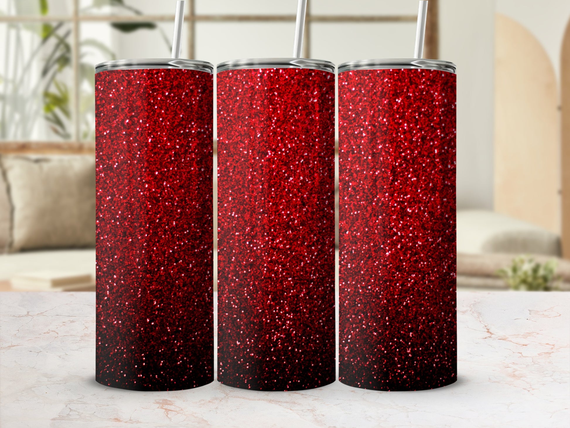 Three red glitter tumblers with straws on a marbled surface.