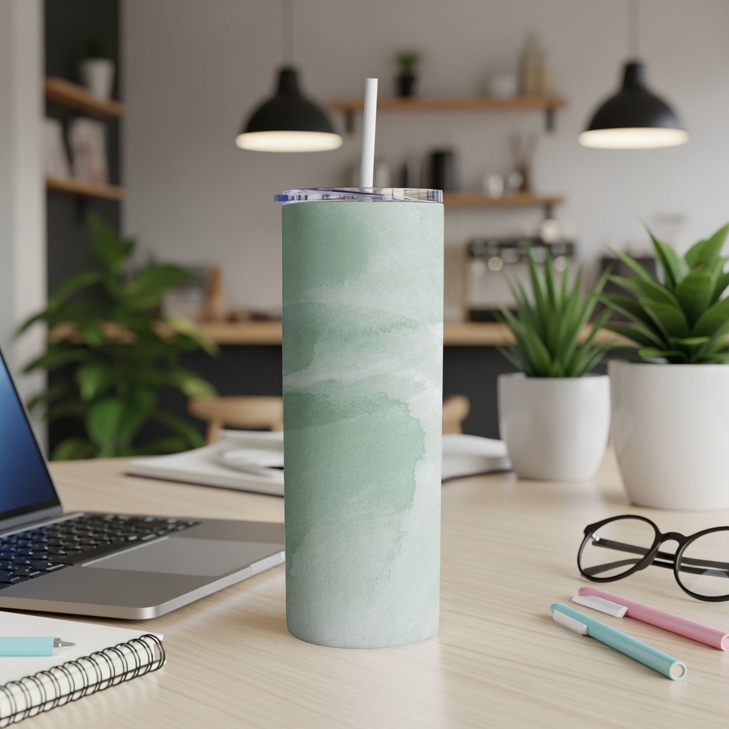 Mint green watercolor pattern tumbler with white straw on a desk.