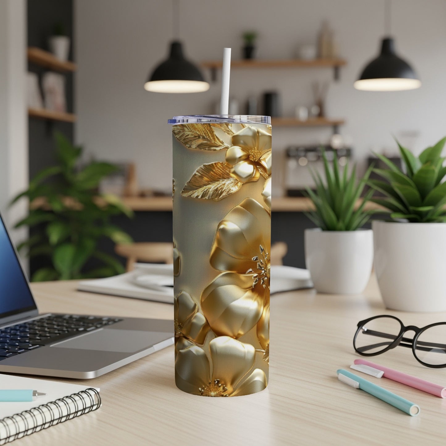 Gold floral tumbler with straw on a desk next to a laptop.